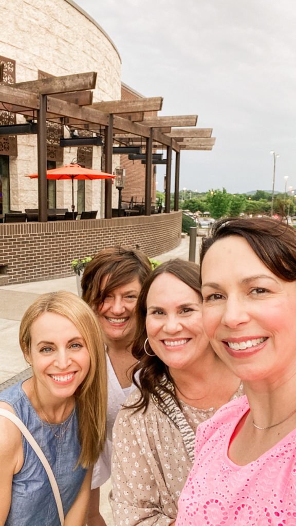 four women pose for selfie by restaurant