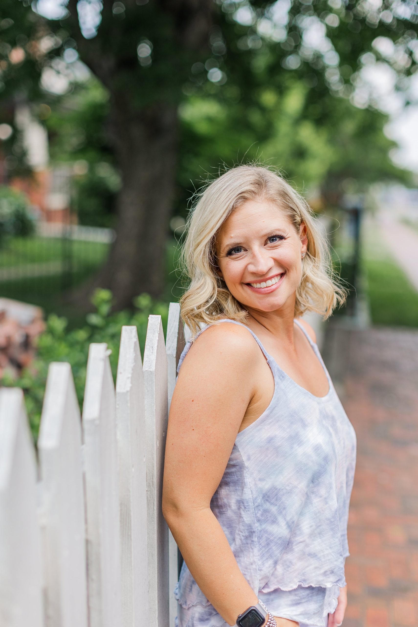 woman leans against white picket fence during TN branding photos