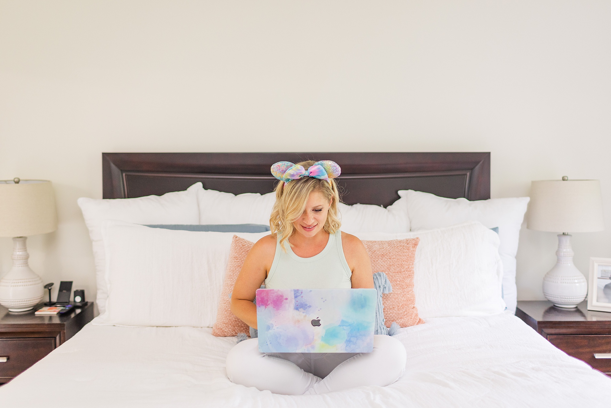 Disney planner and photographer works on laptop in bed during branding session