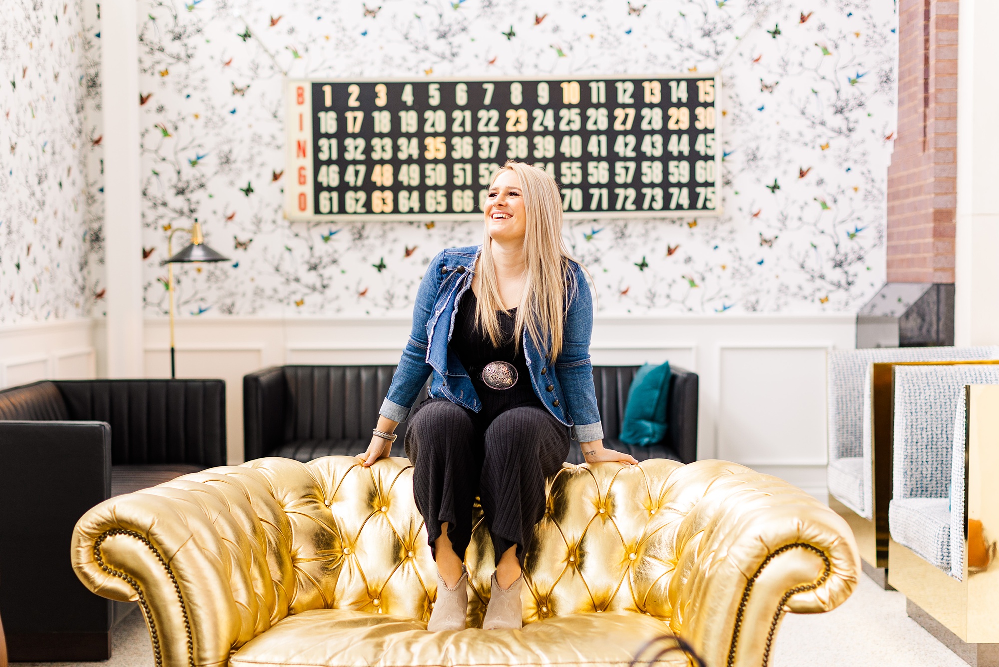 woman sits on the back of gold couch at the Graduate Hotel during branding photos