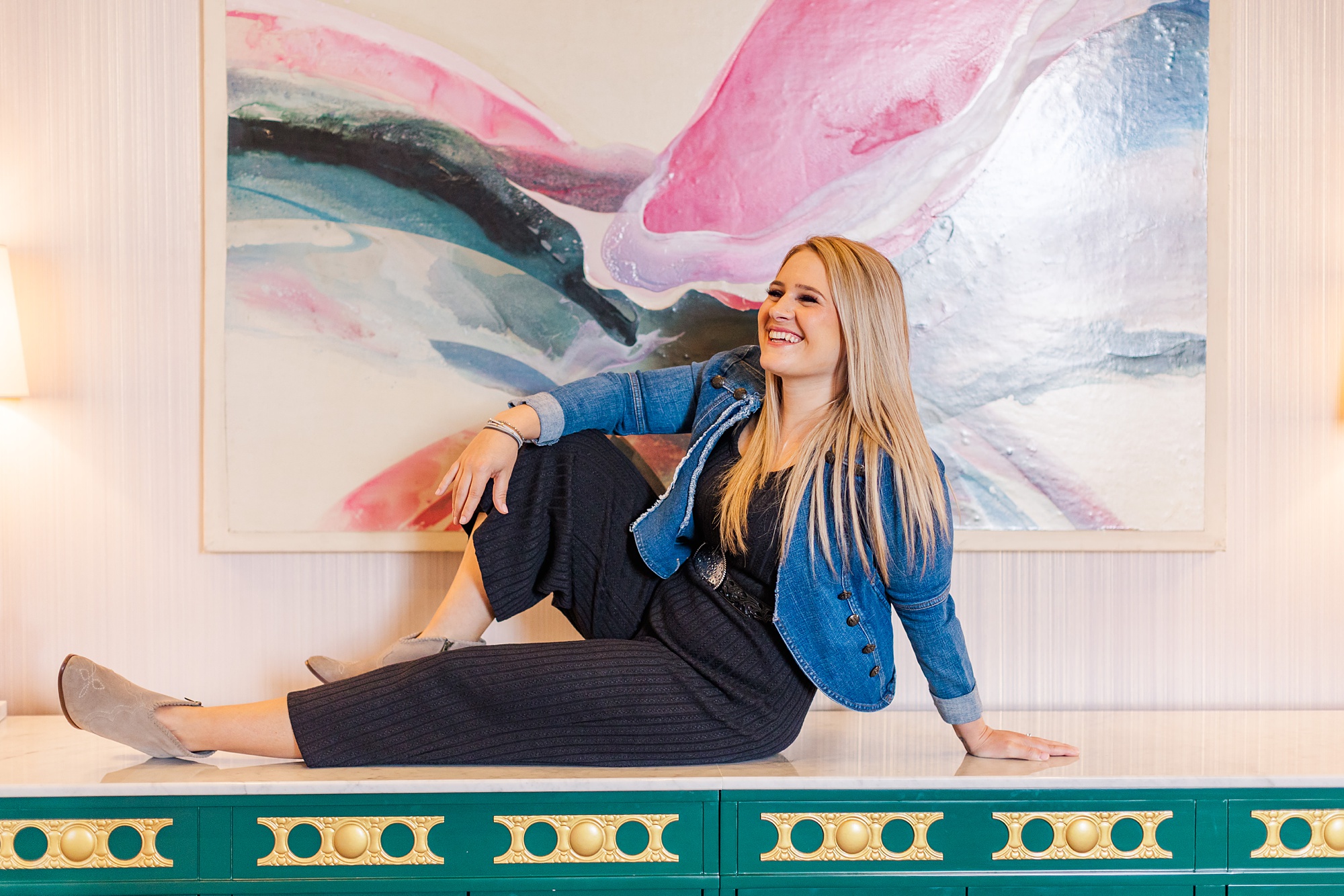 woman sits on green cabinet by art at the Graduate Hotel
