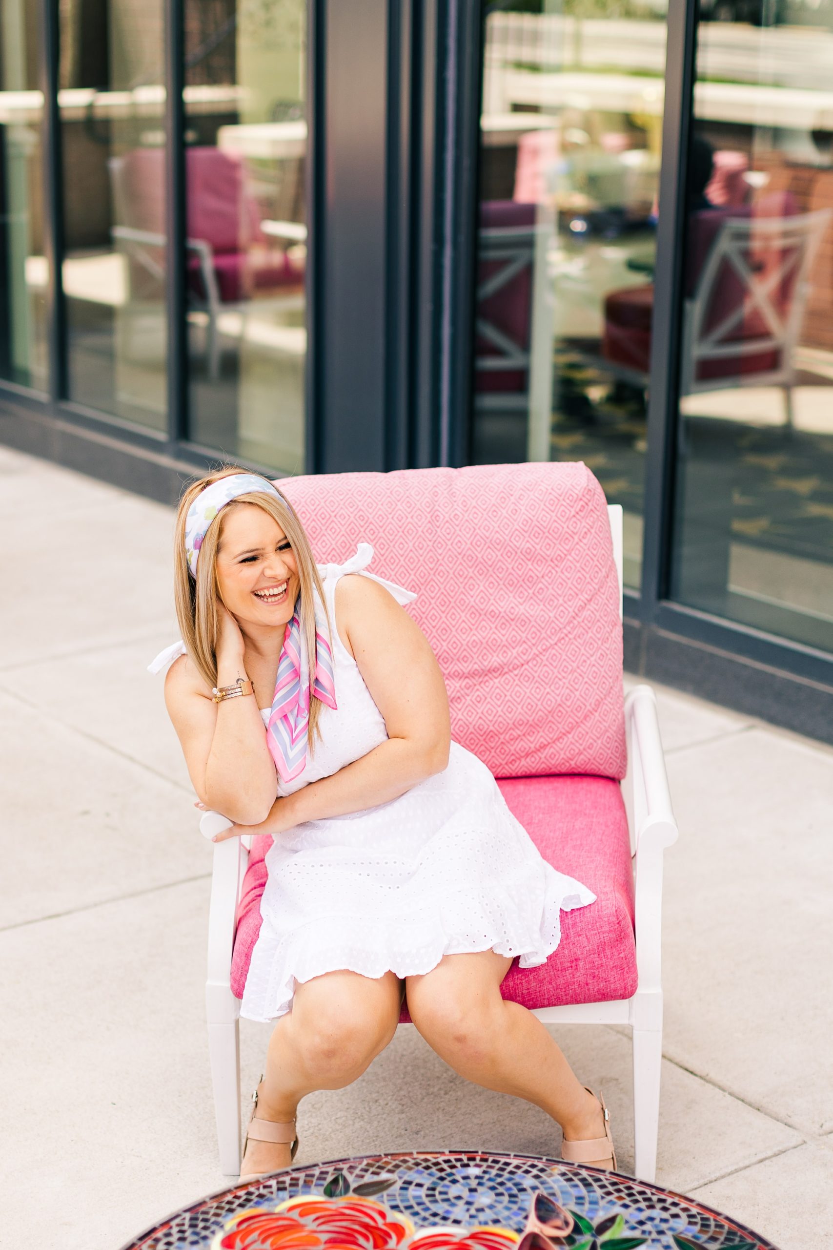woman sits in bright pink chair in Nashville TN laughing