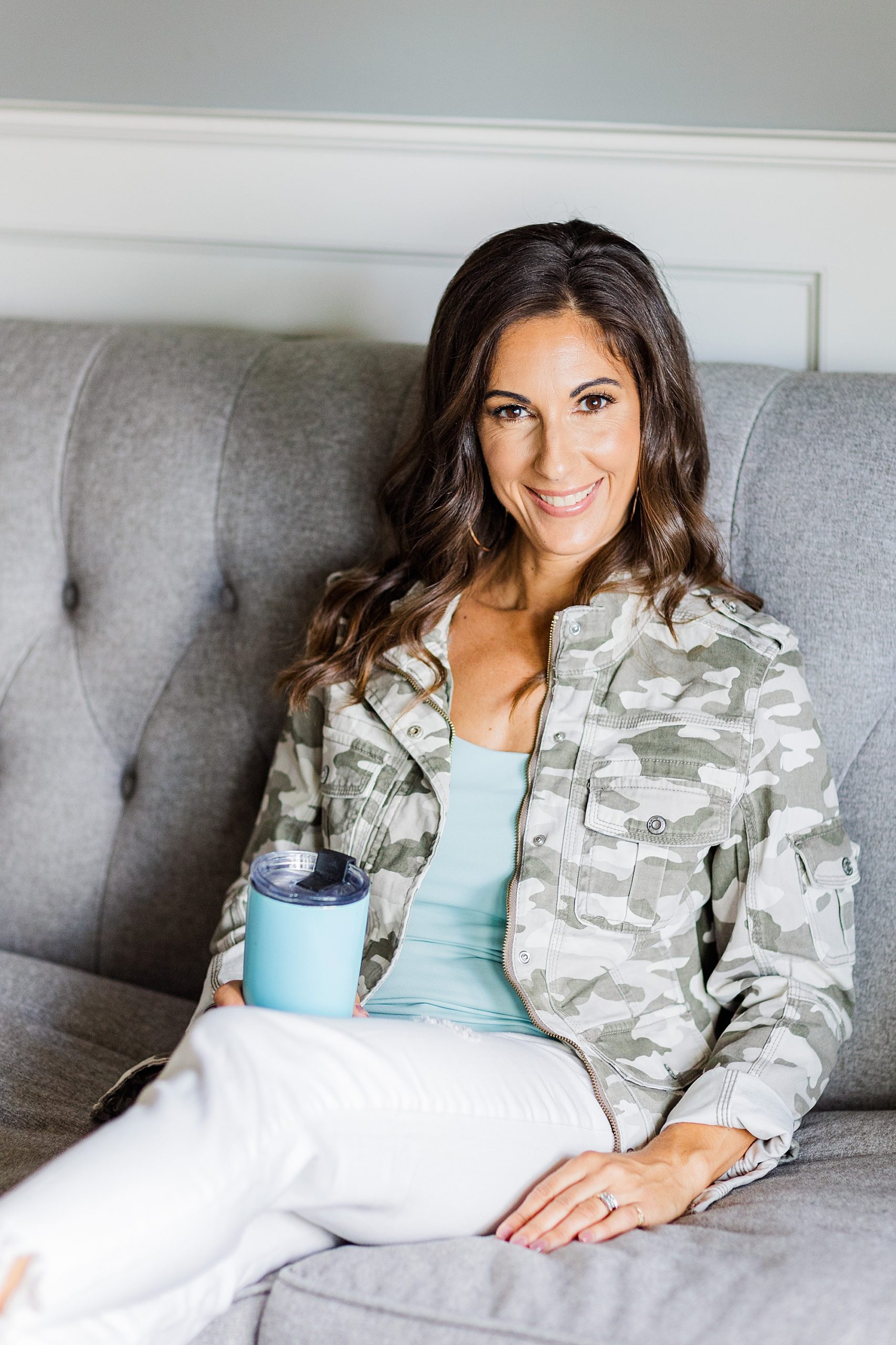 woman in army jacket sits on couch holding blue cup during Franklin branding photos