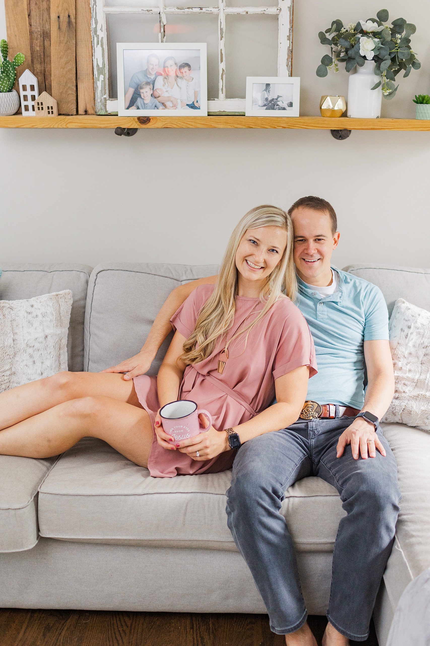 photographer sits on couch with husband during branding session
