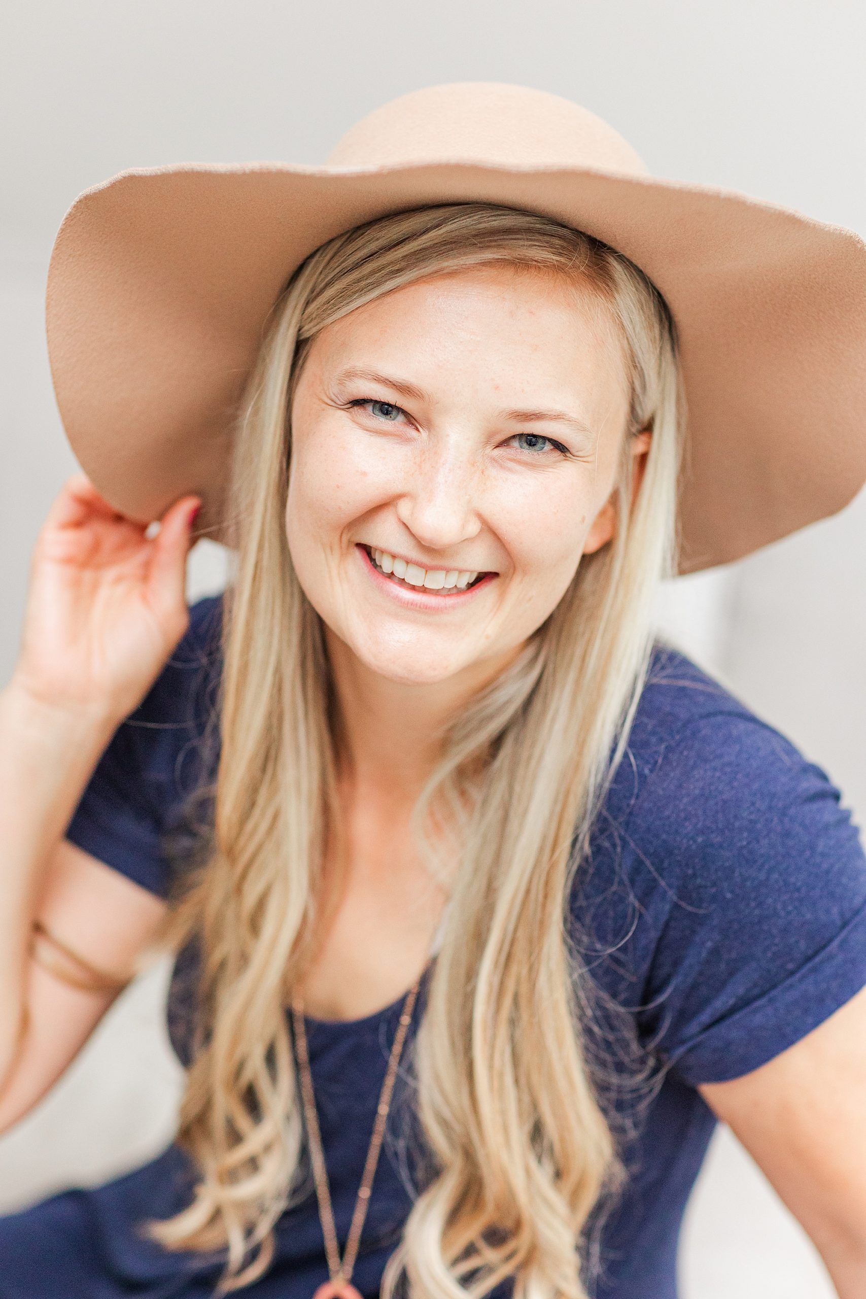 woman in wide brimmed hat smiles at camera
