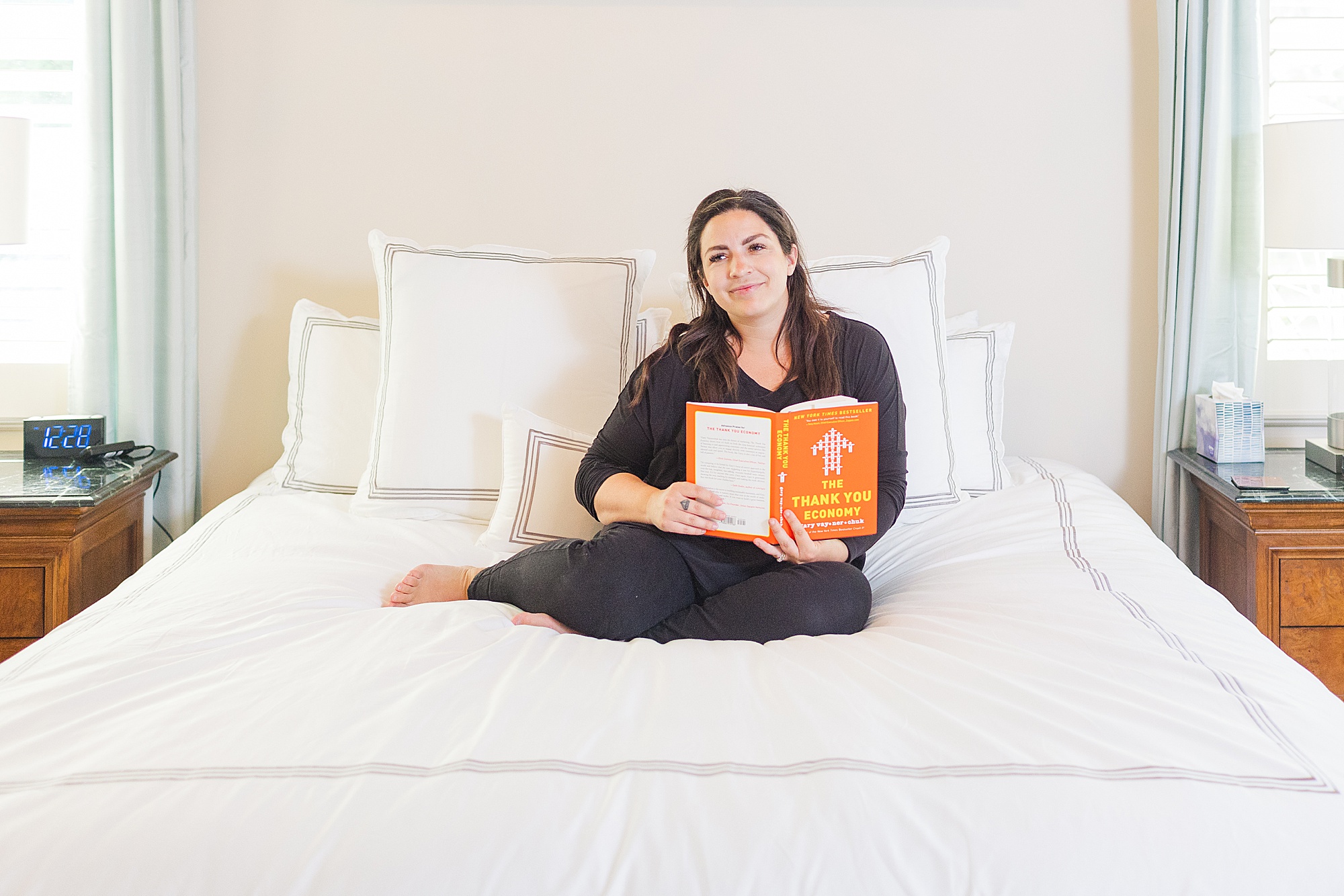 woman sits on bed reading book