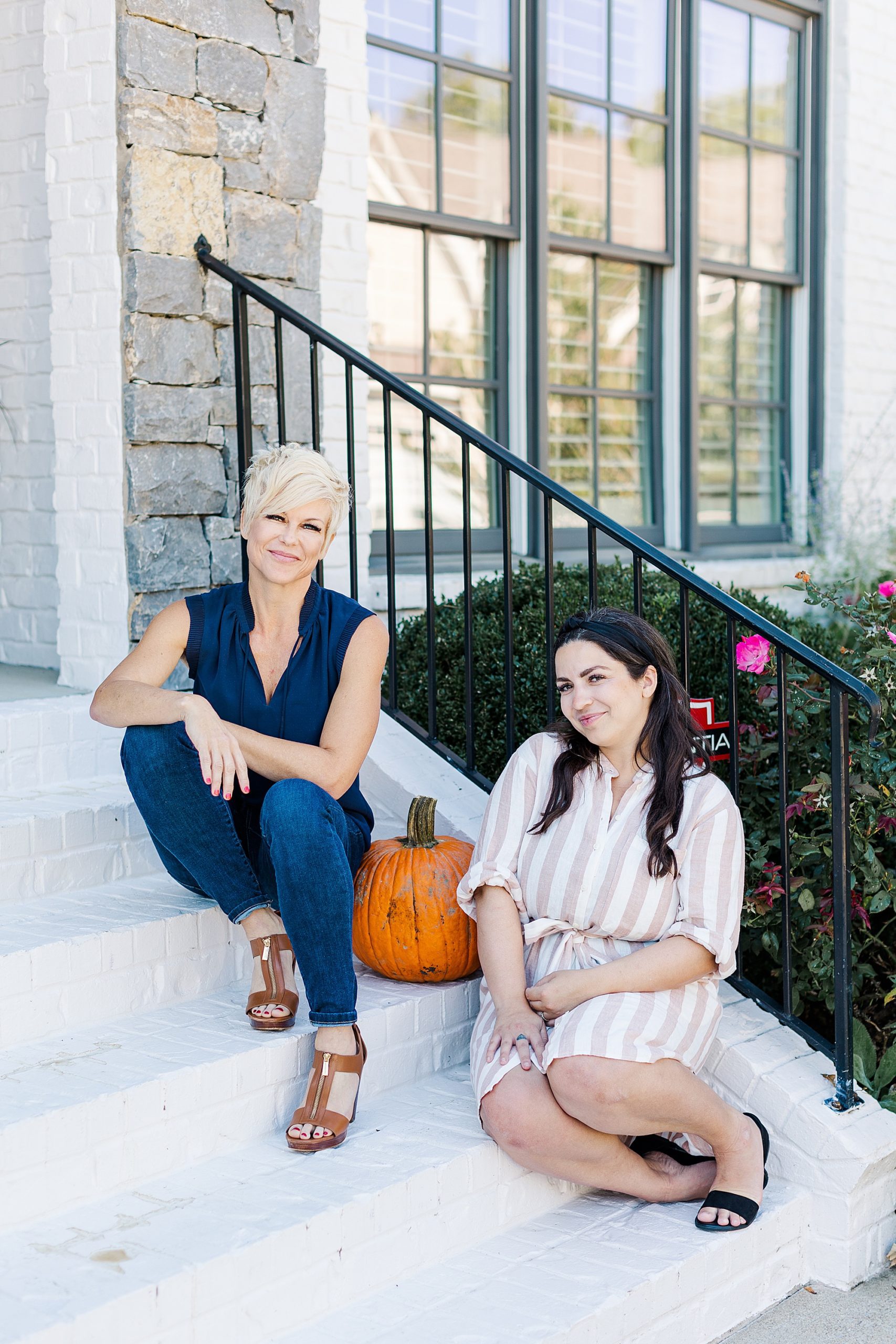 real estate agents sit on front step by pumpkins