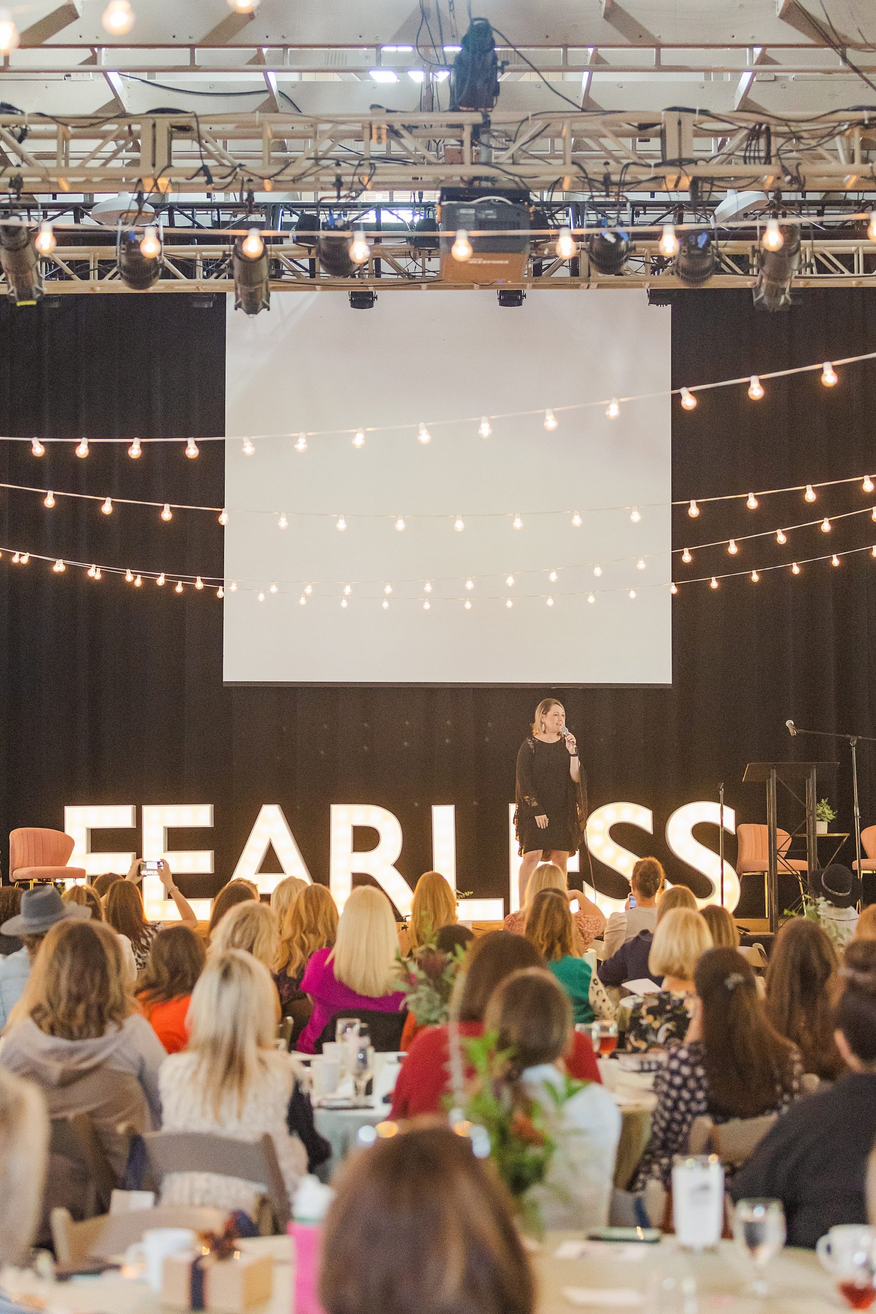 woman speaks on stage with FEARLESS sign behind her