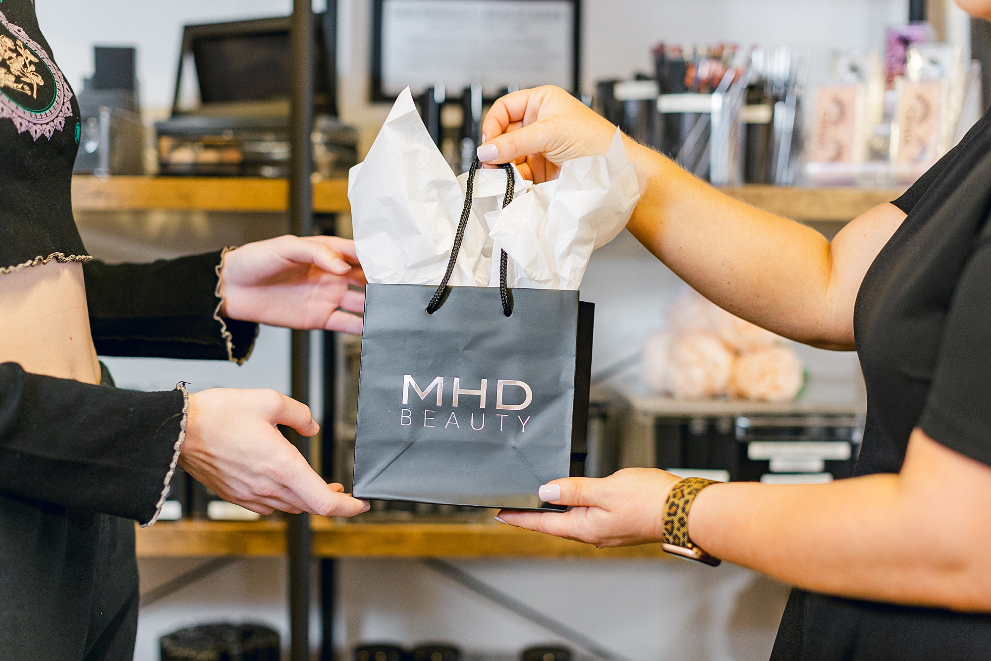 woman hands client a bag with MHD brand on the front