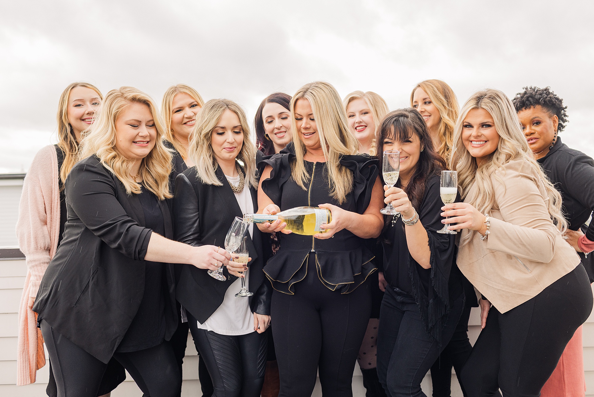 team leader pours champagne for makeup artists