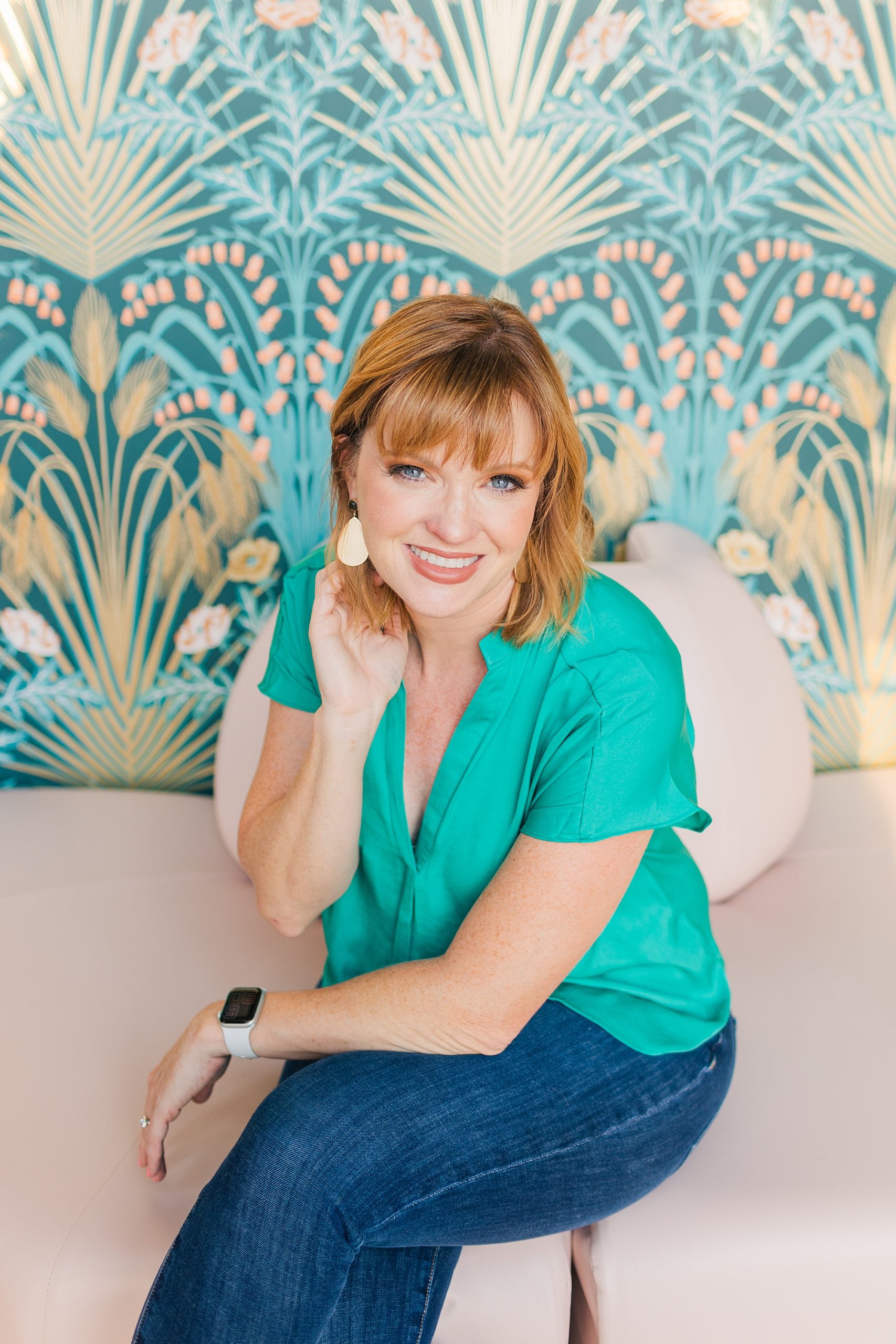 woman in teal shirt sits by colorful wall during branding portraits in Nashville TN