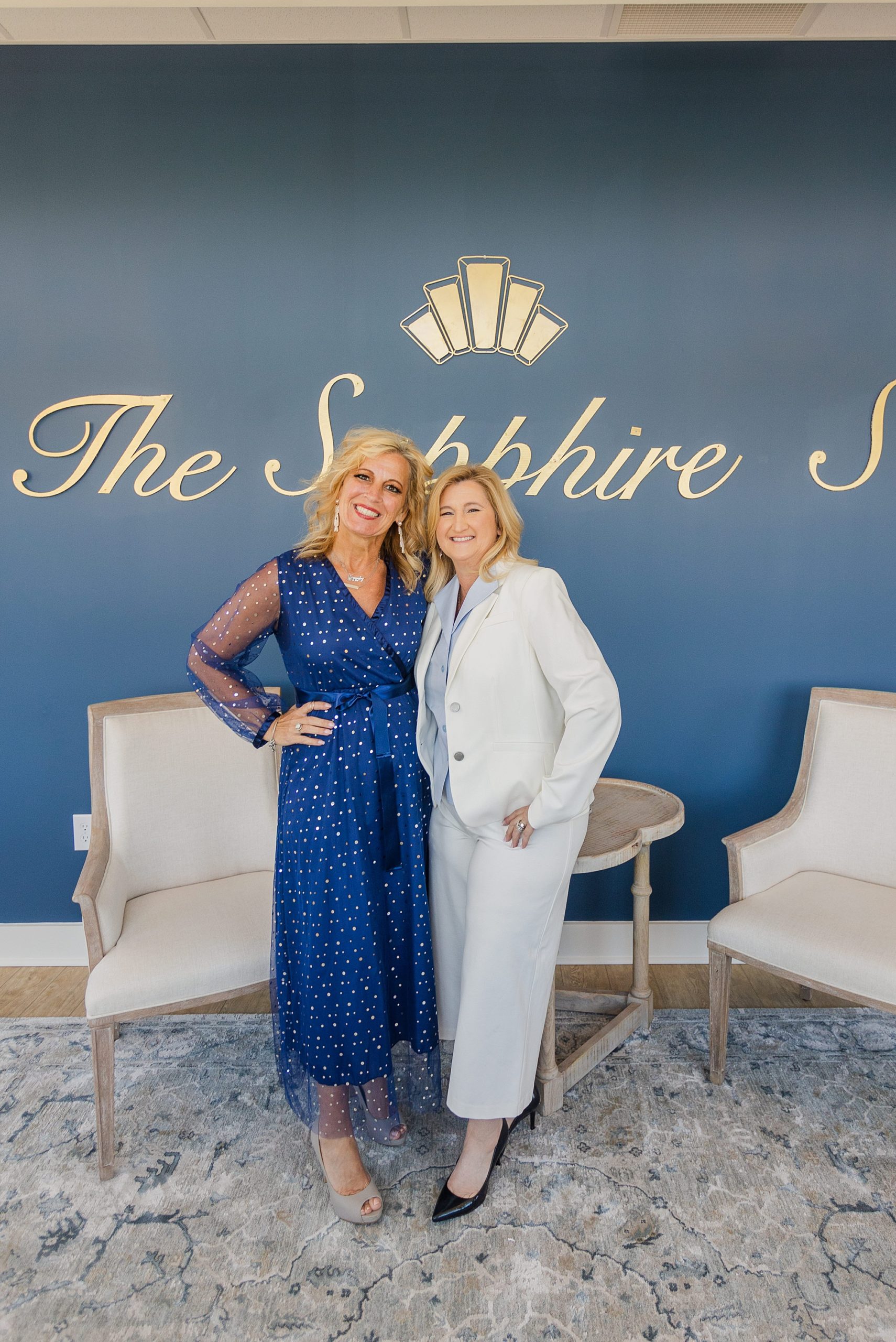 two women pose by blue wall at The Sapphire Suite