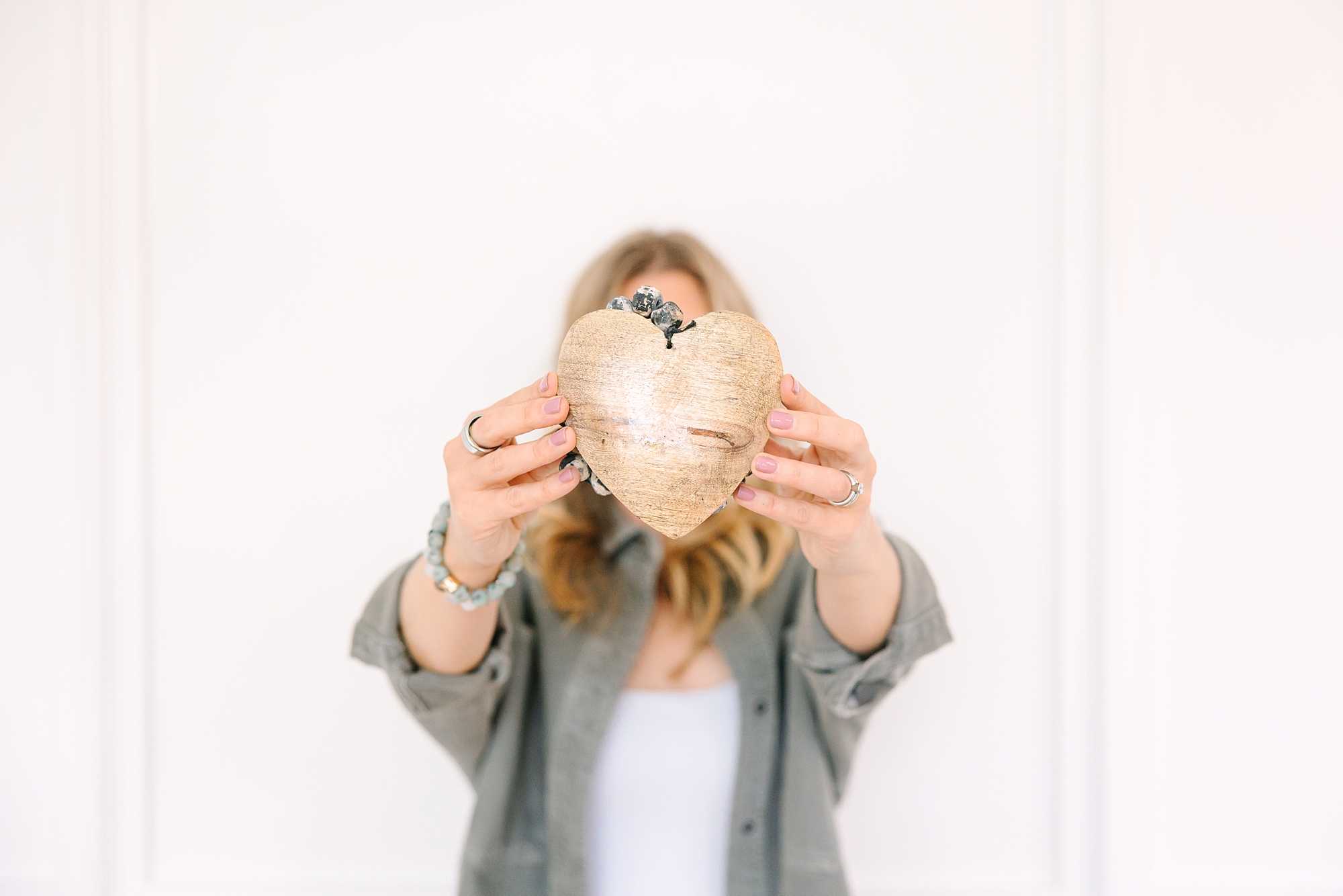 fertility-focused health coach holds out wooden heart in front of face