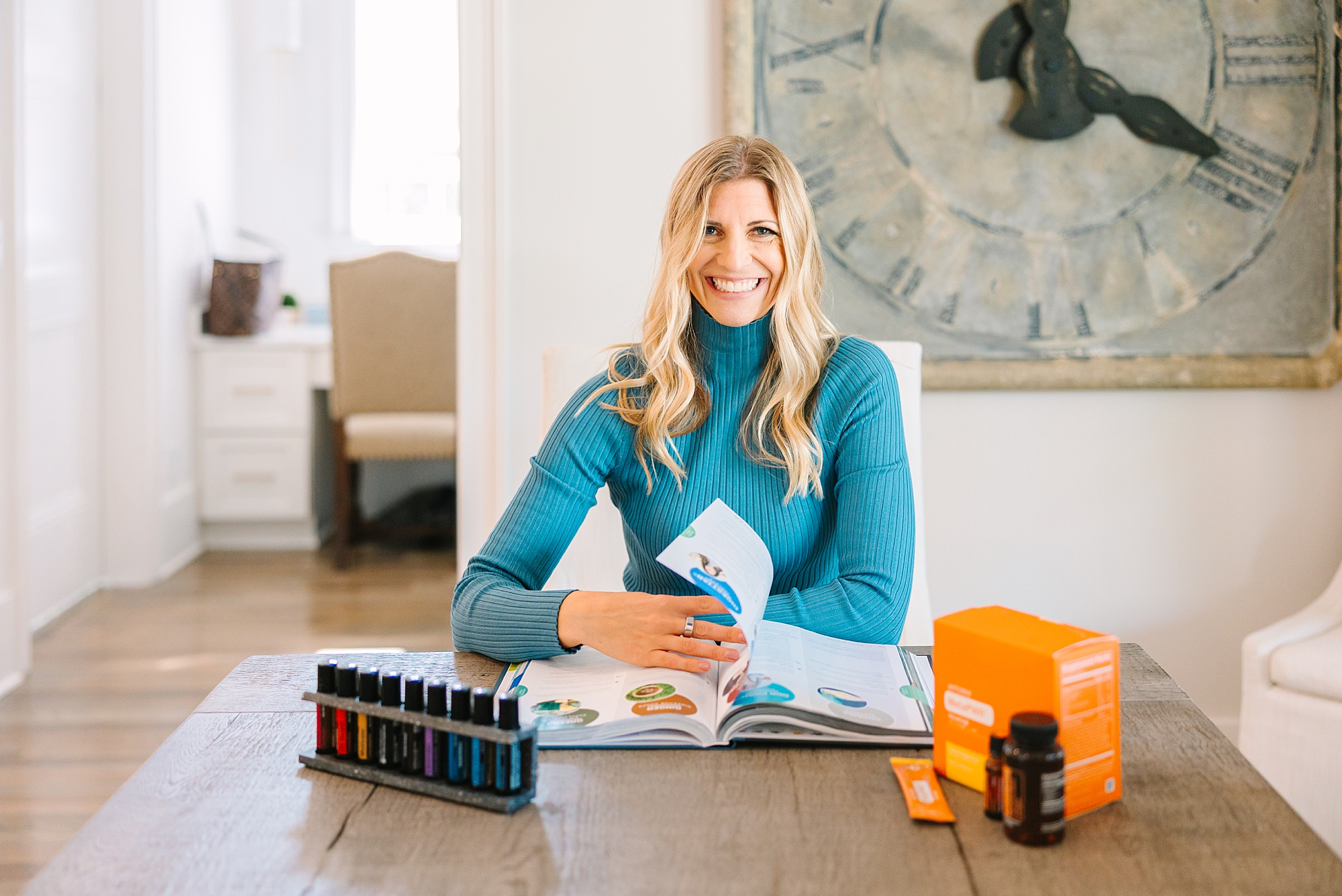 health coach flips through books at dining room table with oils