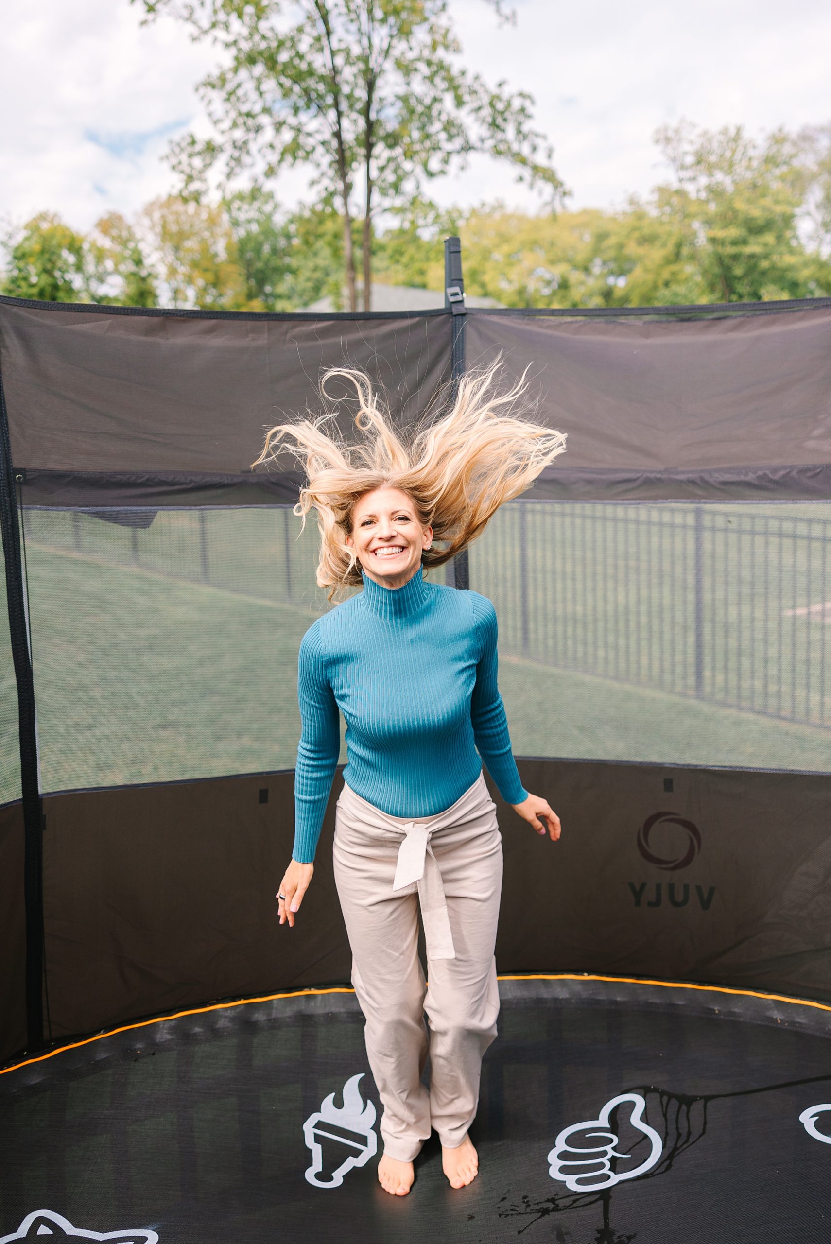 woman jumps on trampoline with blonde hair flying around her