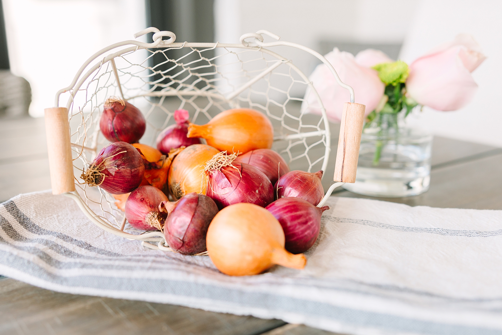 onions spill out of white basket on countertop