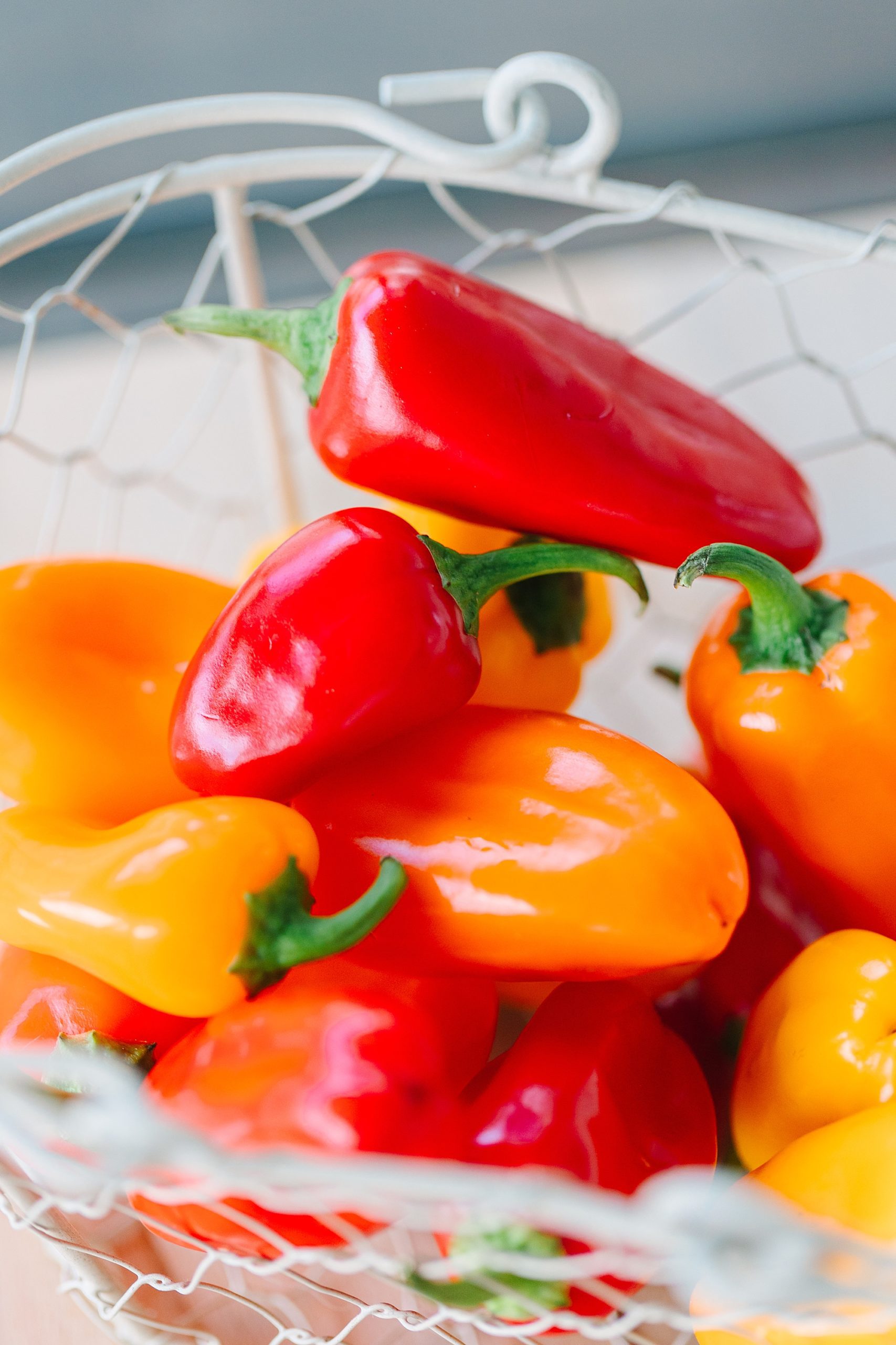 red and orange peppers lay in white basket