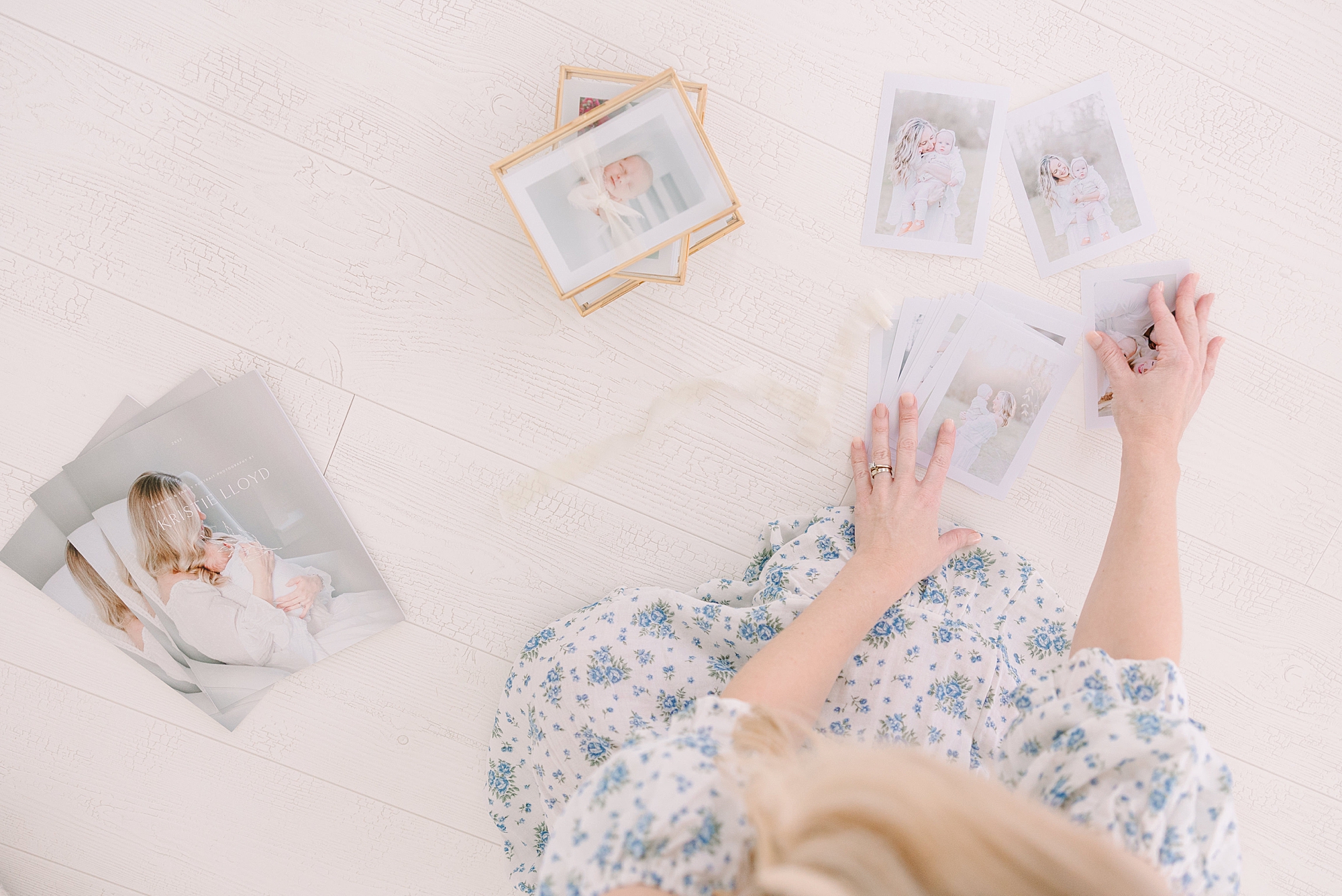 woman sits with prints of photos on floor
