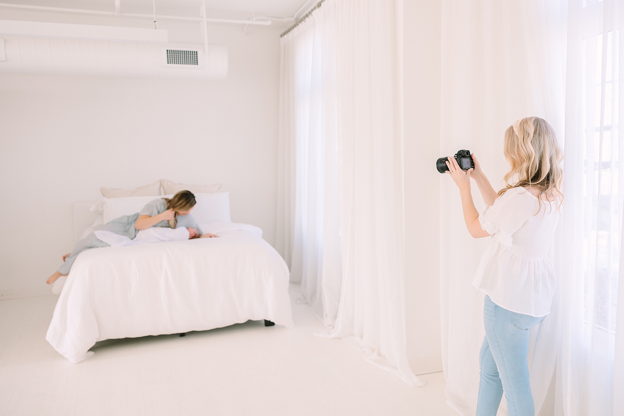 photographer takes photo of mom and baby on bed