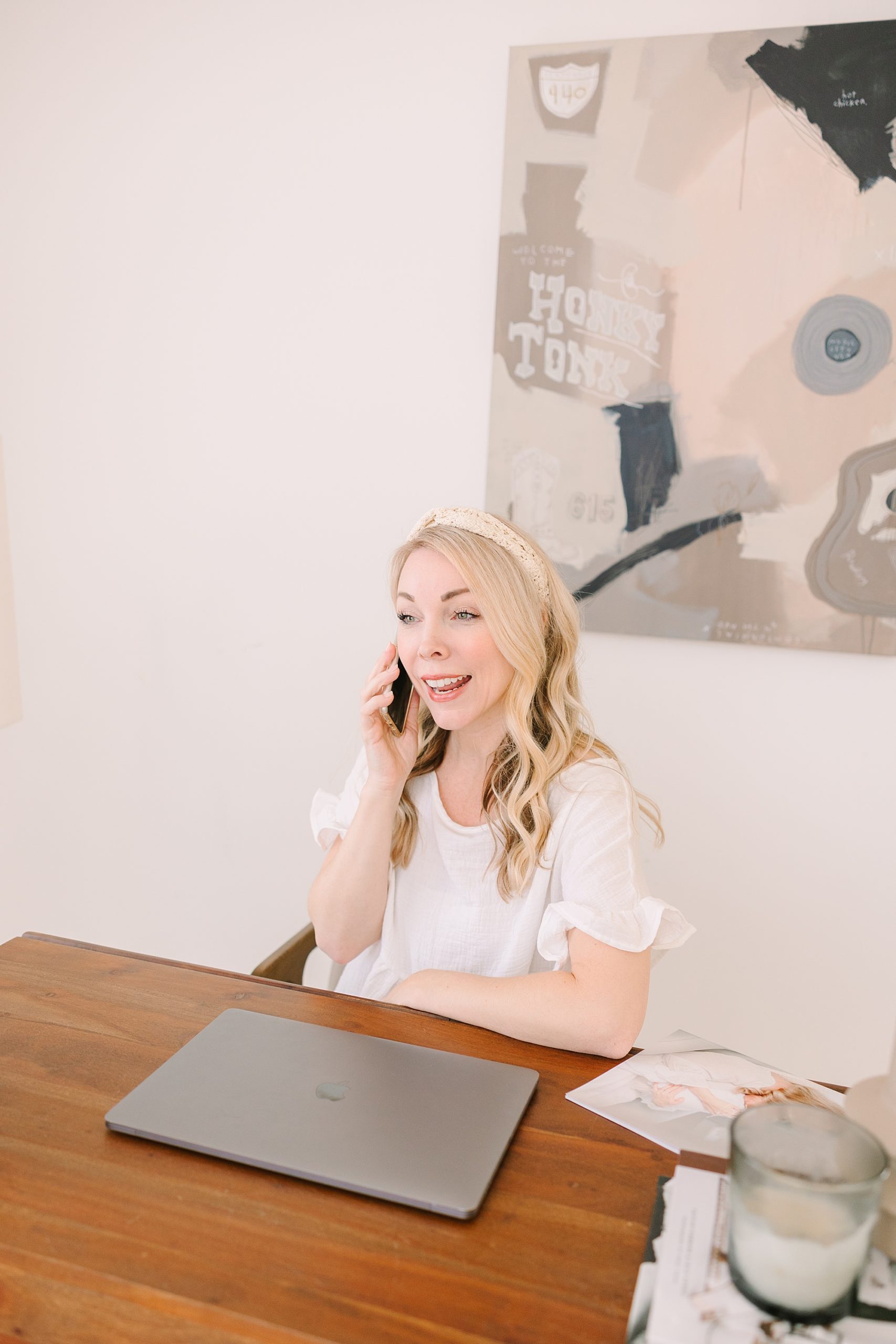 woman talks on phone sitting at desk during Studio Blanc branding photos in Nashville, TN