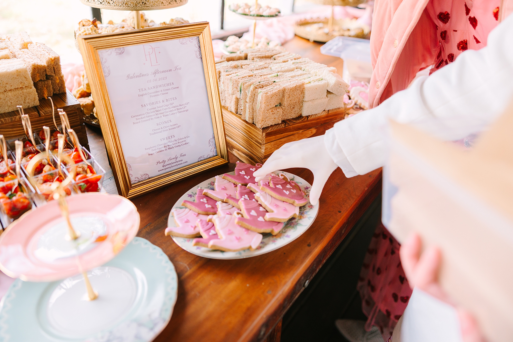 woman reaches for pink cookie during Galentine's Day Tea Party
