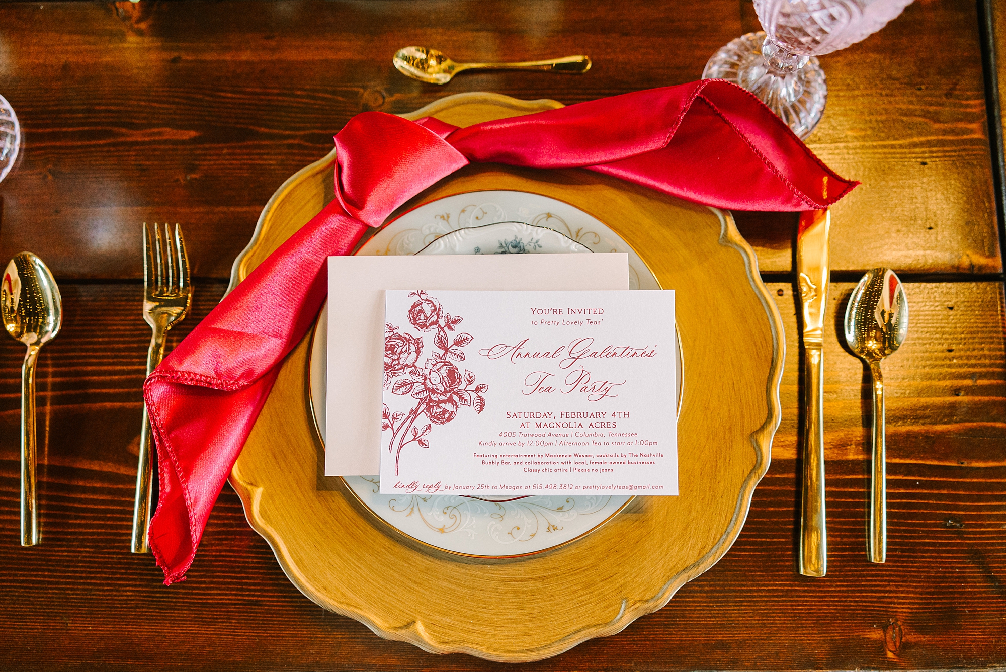 place setting for tea party with red napkin on gold charger