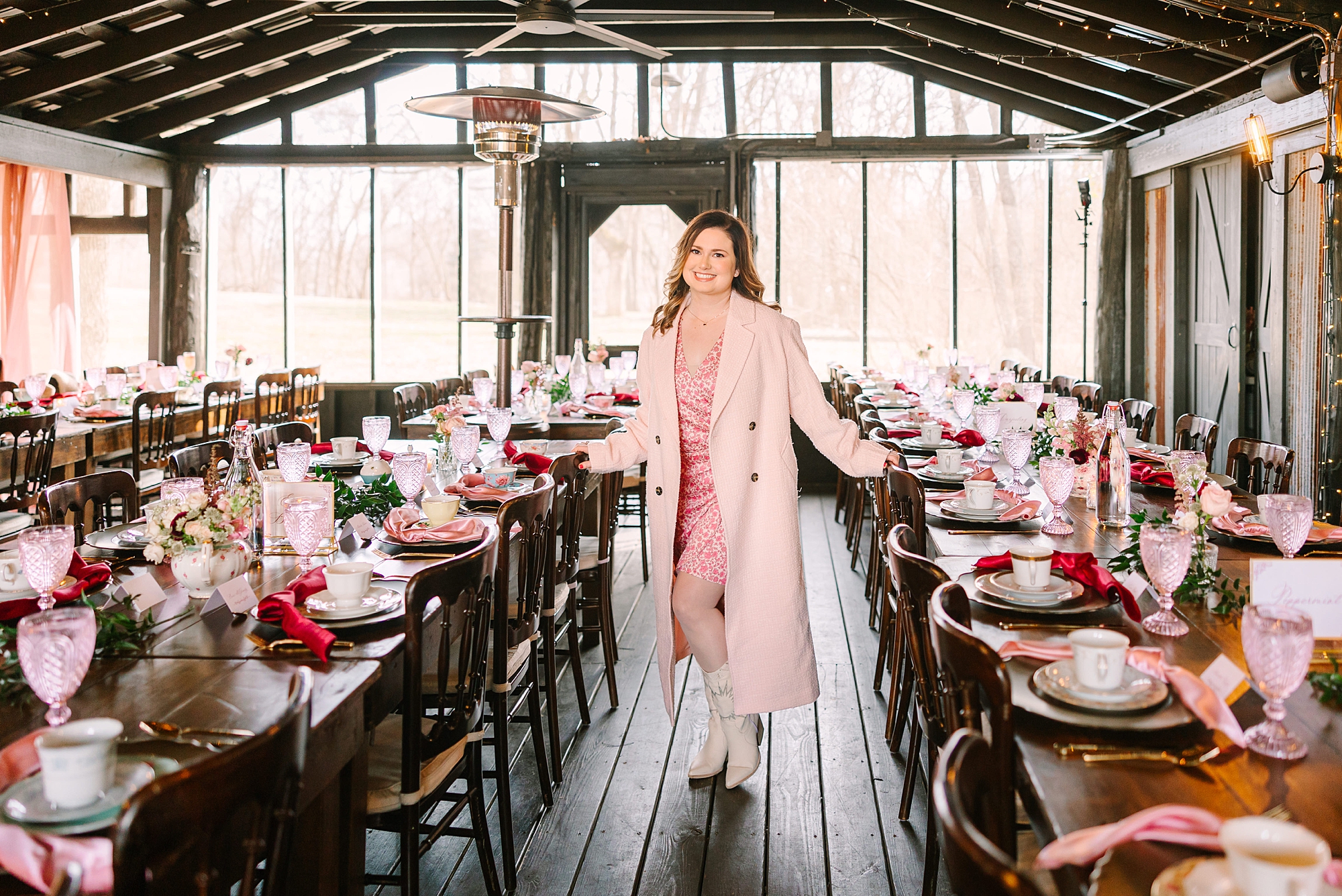 woman in pink jacket poses among rows of tables at Magnolia Acres