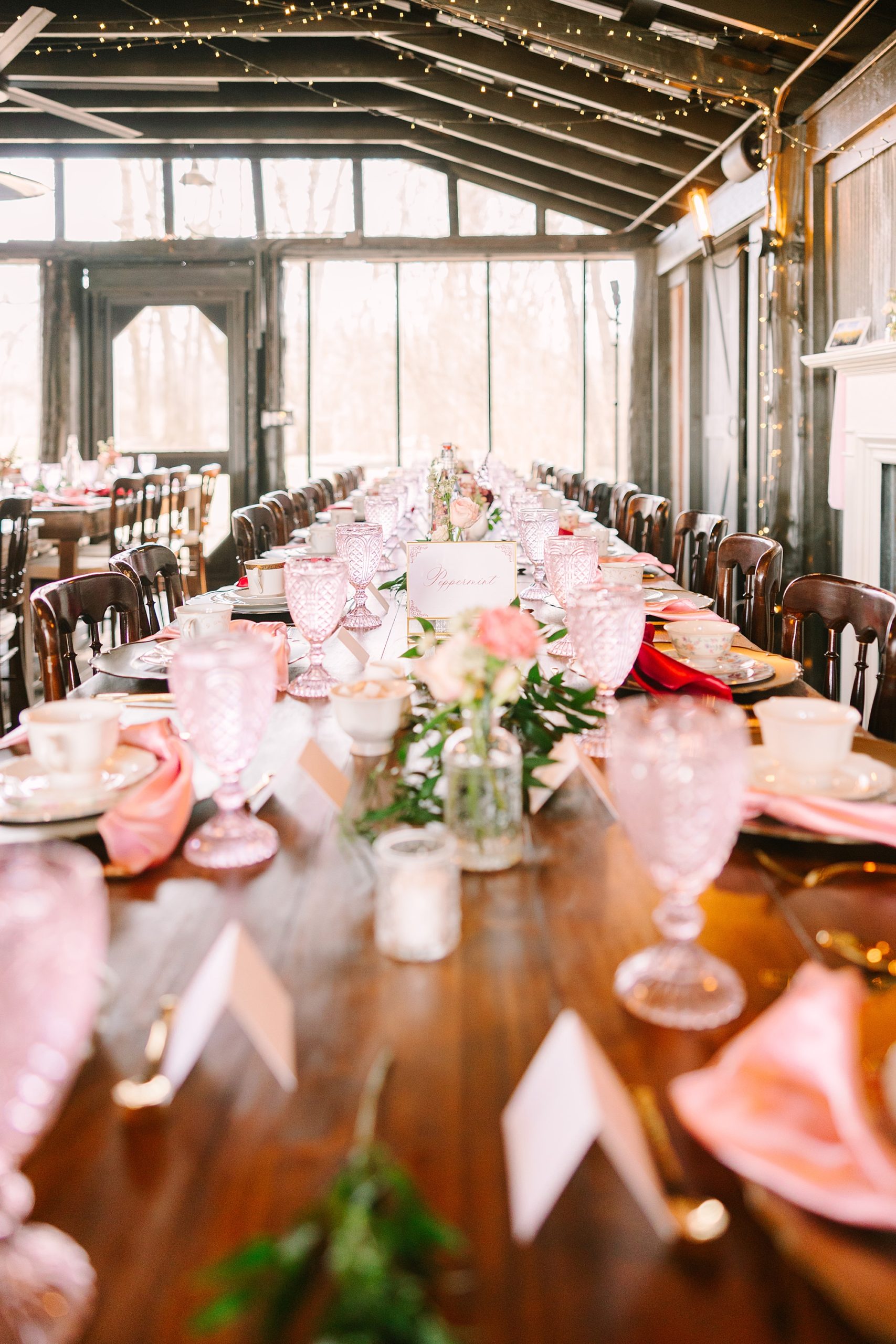 place settings on family style wooden table with pink glasses