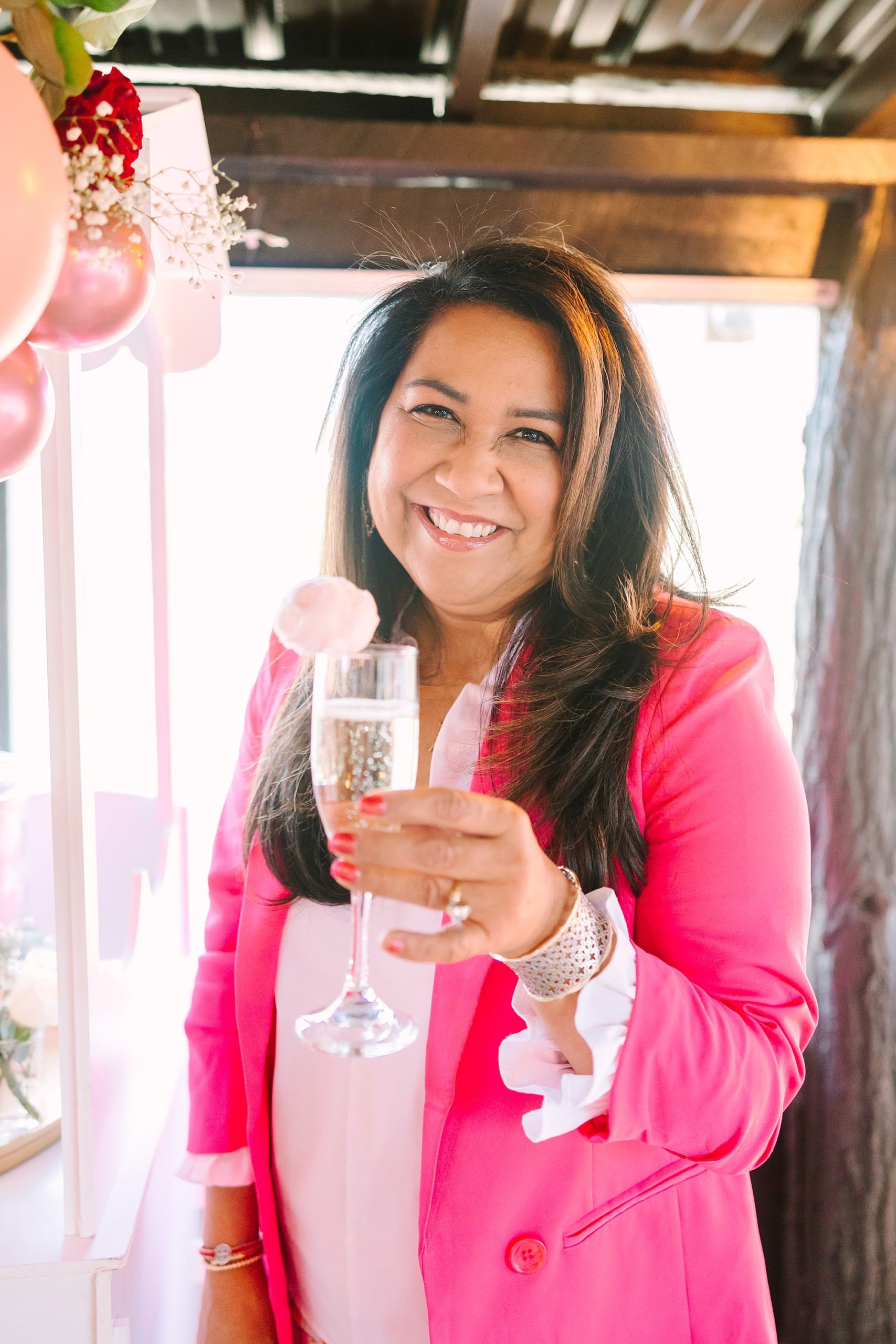 woman in pink blazer holds champagne during tea party