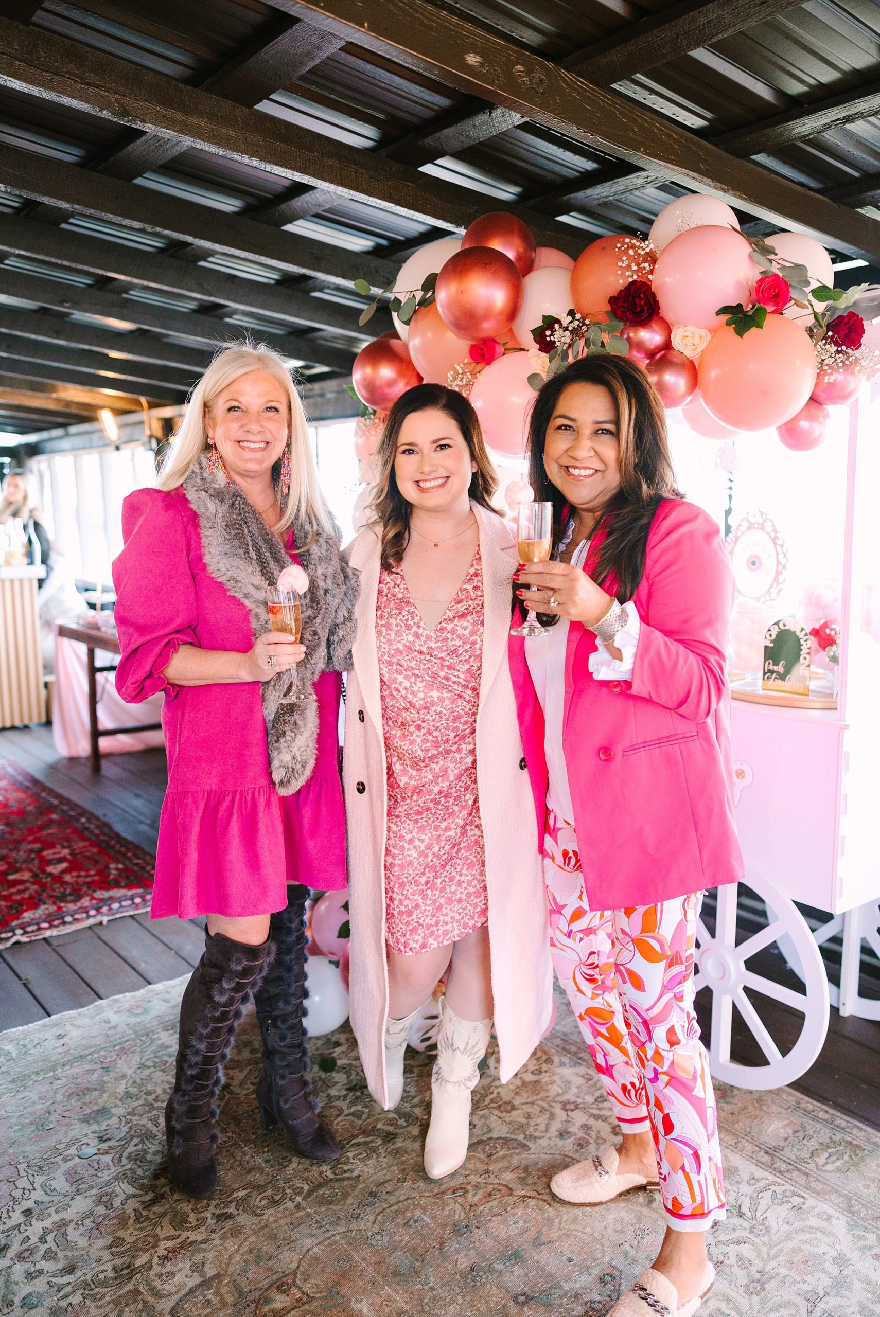 women in pink dresses hold up tea cups