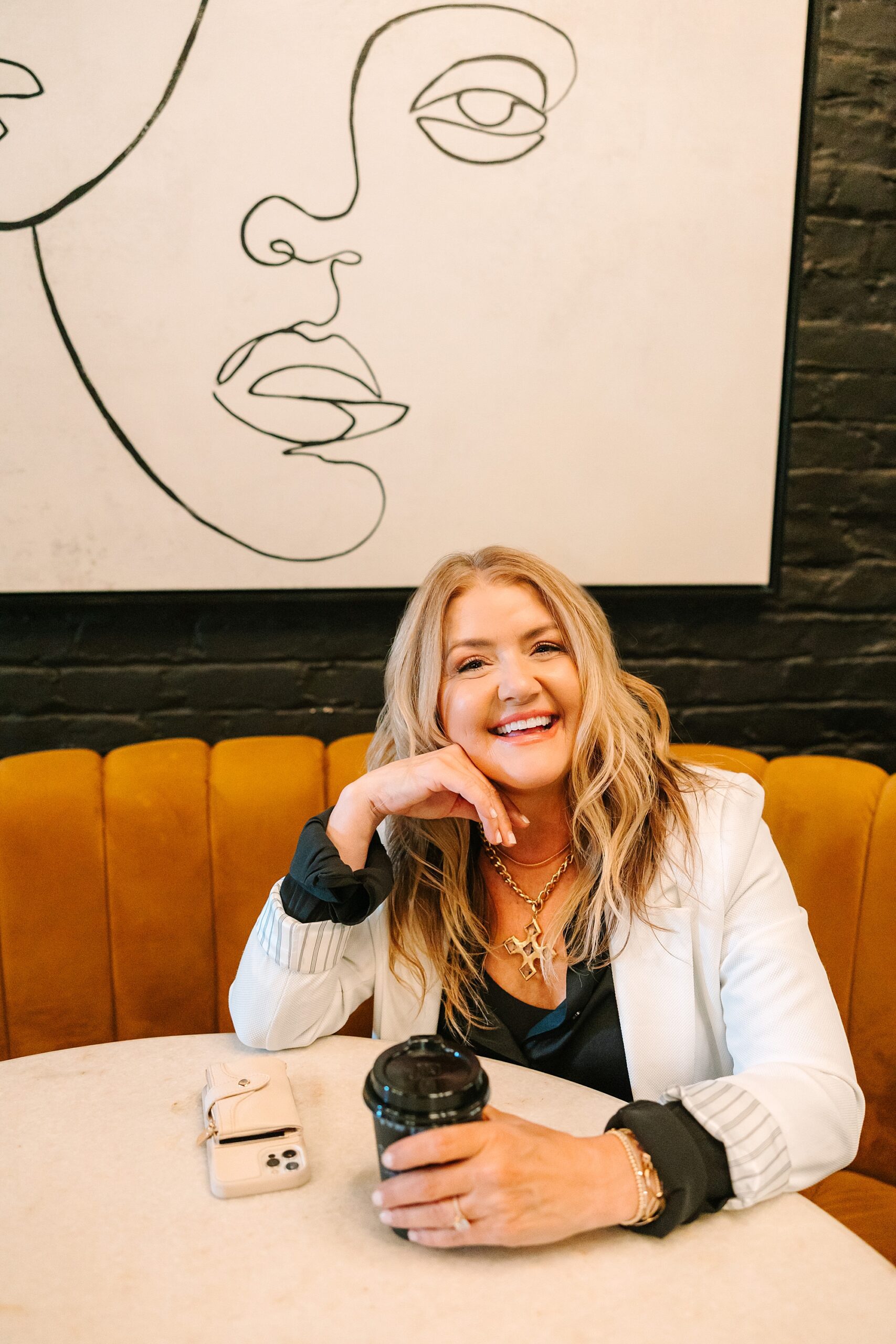 blonde woman laughs during coffee break at shop