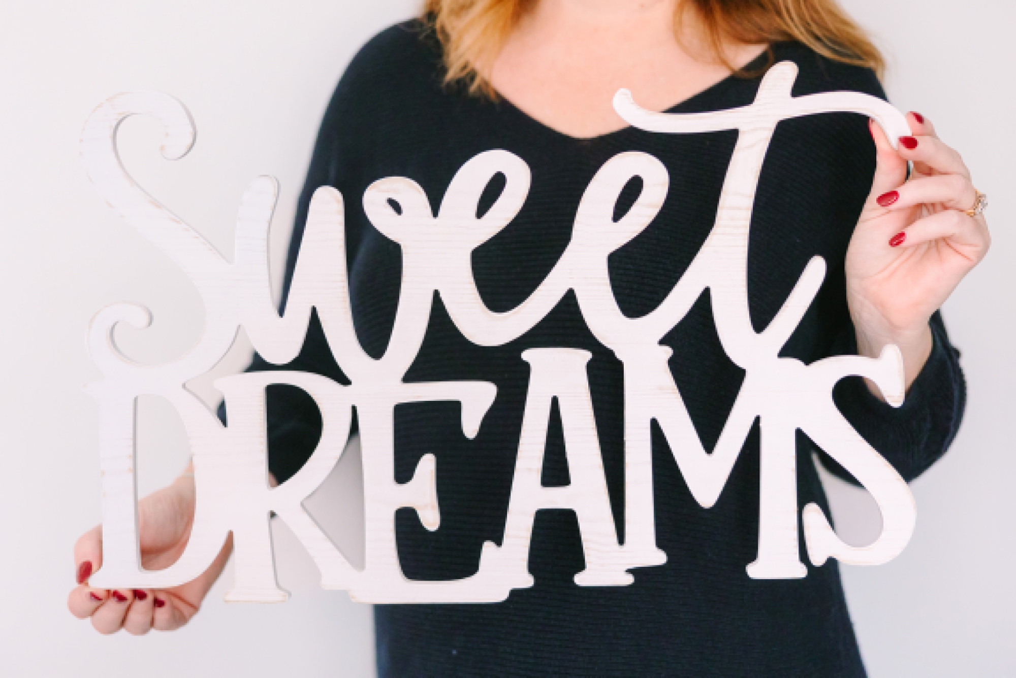 woman holds sweet dream sign in front of chest