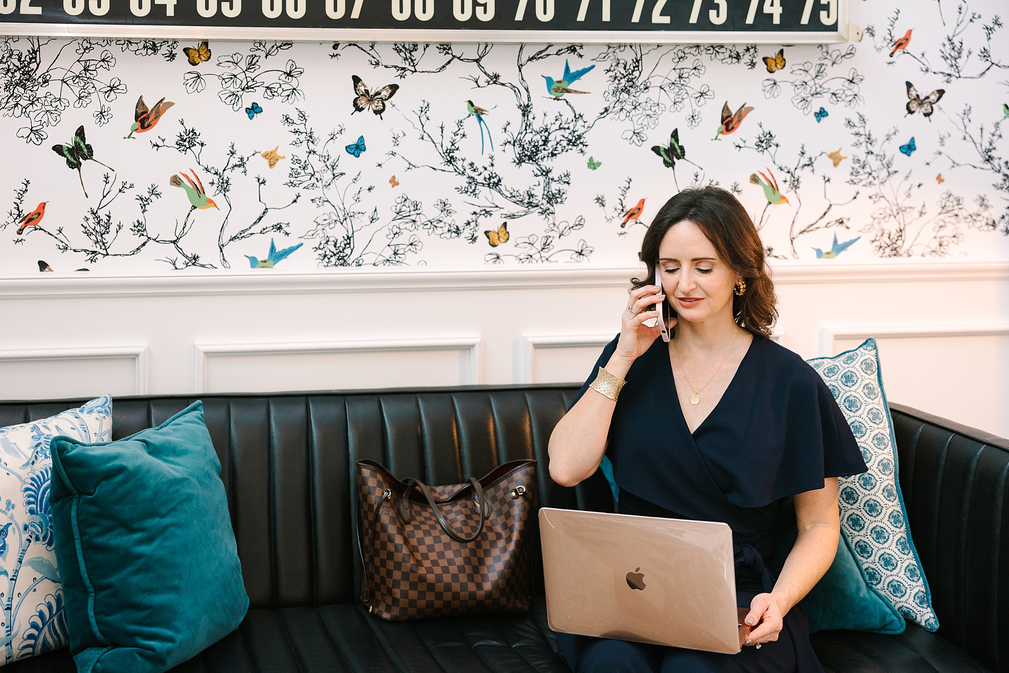 brunette woman in navy dress works on laptop during branding photos