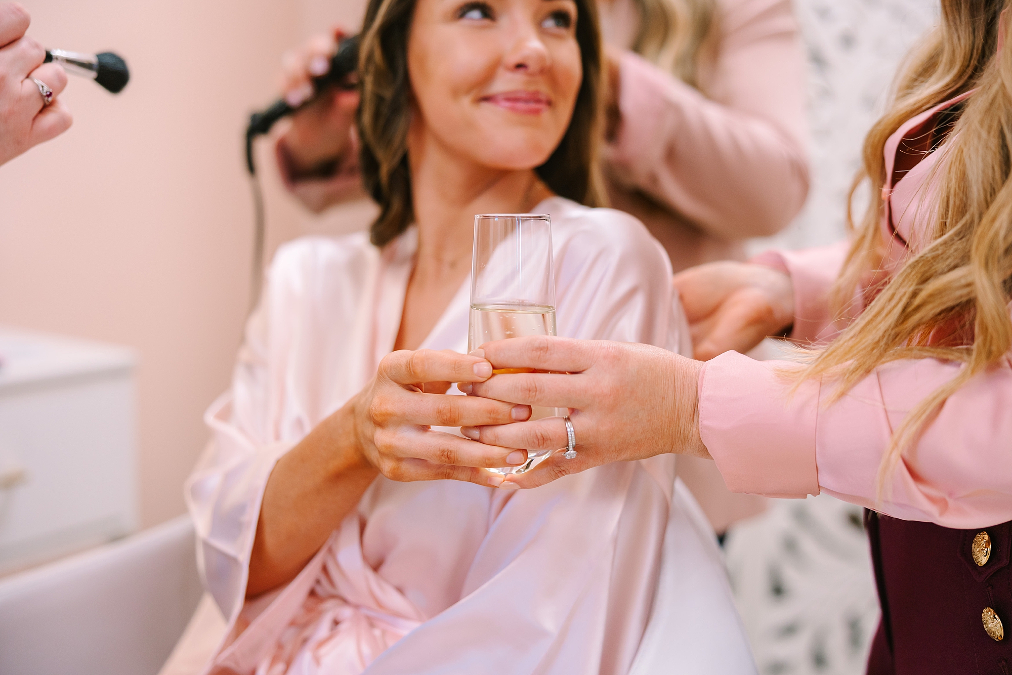woman hands client a glass of champagne during hair appointment