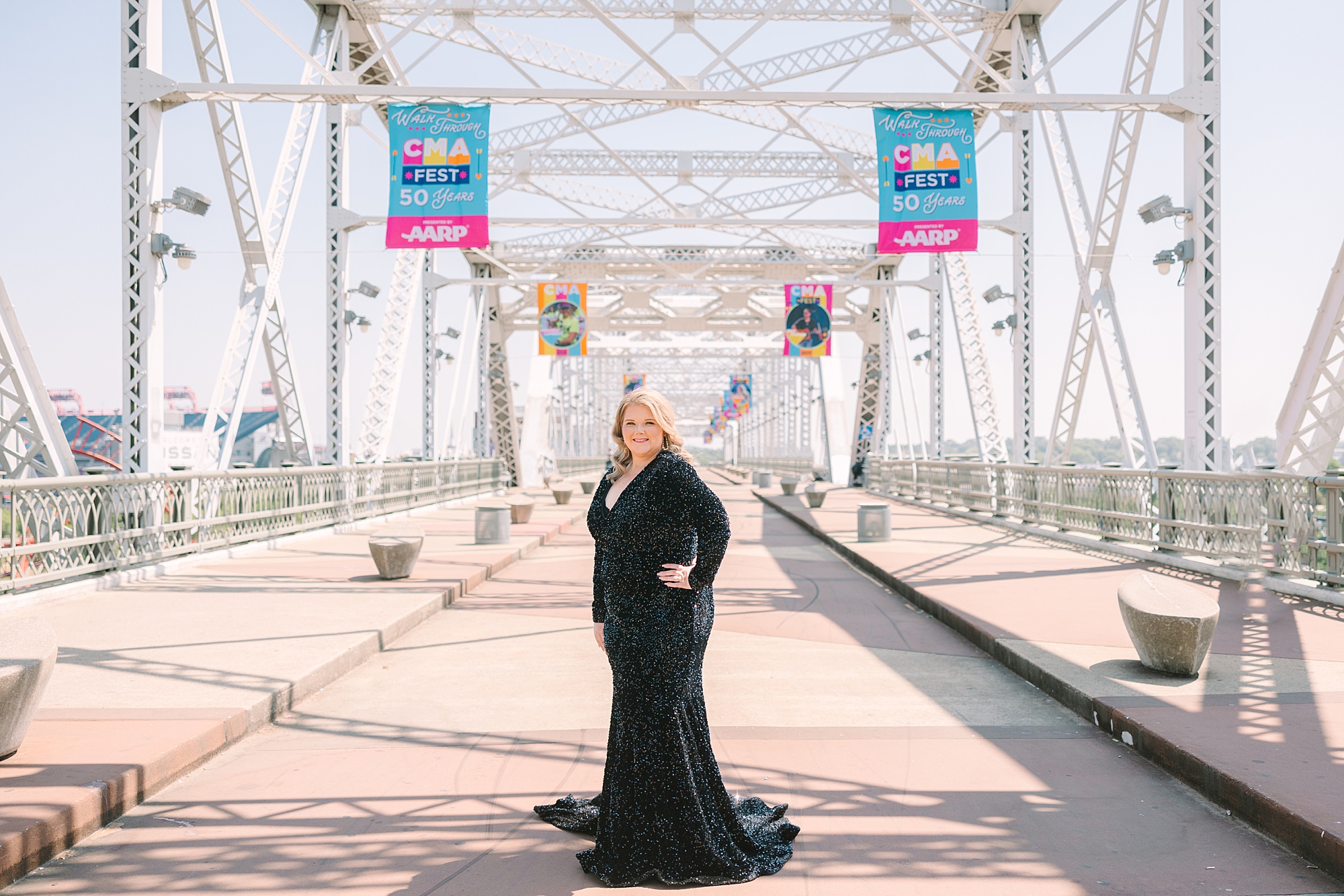 woman in black sparkly dress stands on downtown Nashville pedestrian bridge