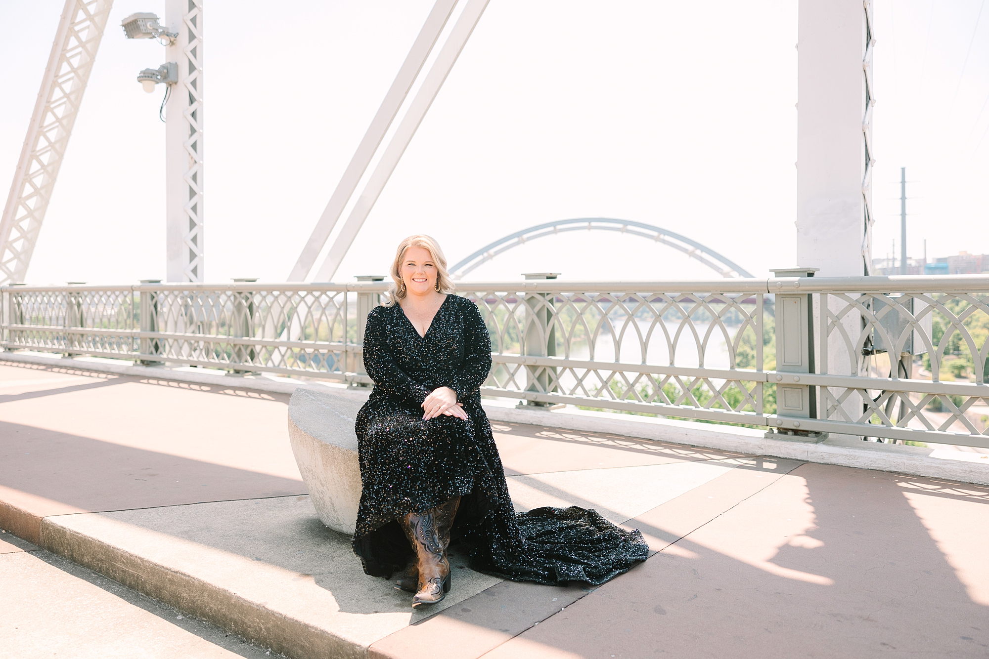 woman sits near railing of downtown Nashville pedestrian bridge