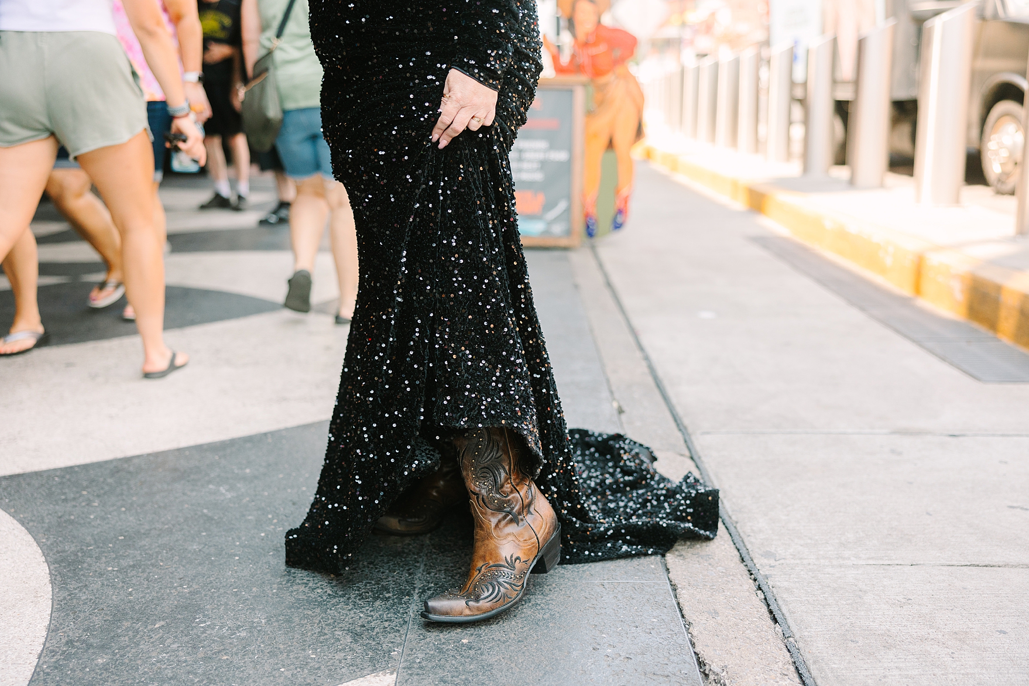 woman in black dress shows off cowboy boots during Downtown Nashville portraits