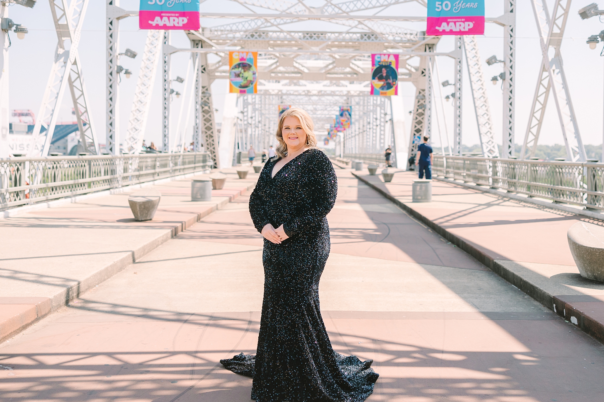 blonde woman in black dress stands on downtown Nashville pedestrian bridge