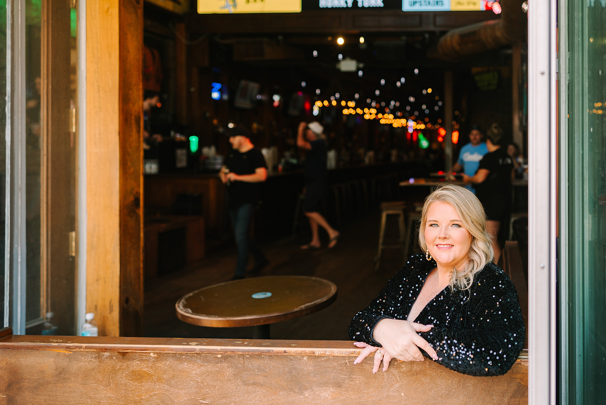 woman leans on wooden bar inside Nudie's, a honky tonk bar in Downtown Nashville