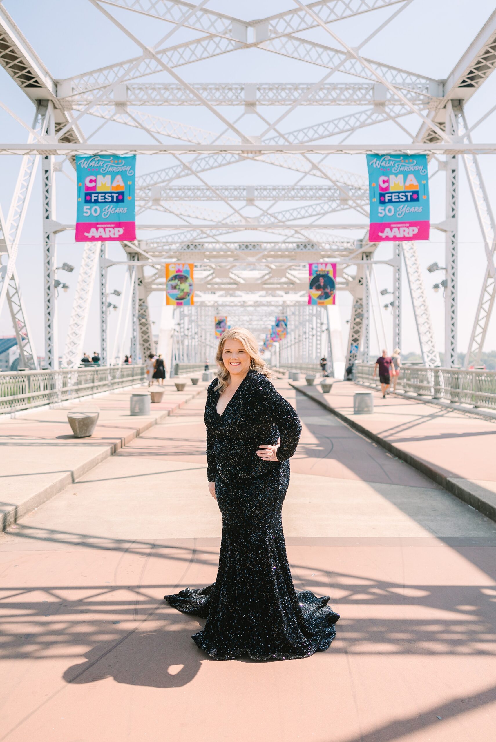 woman in black dress stands on the Downtown Nashville pedestrian bridge