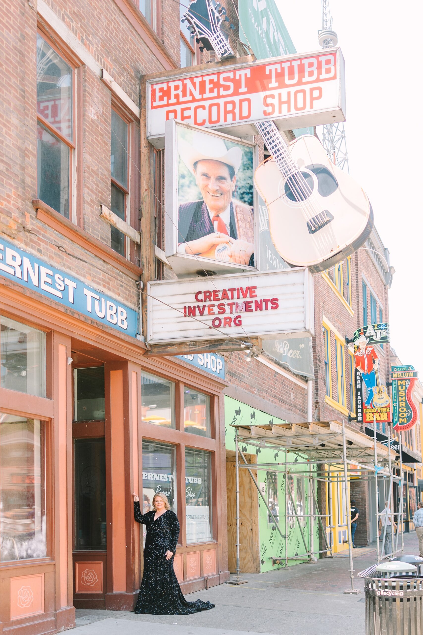woman in black dress poses under Cash sign on Broadway in Downtown Nashville