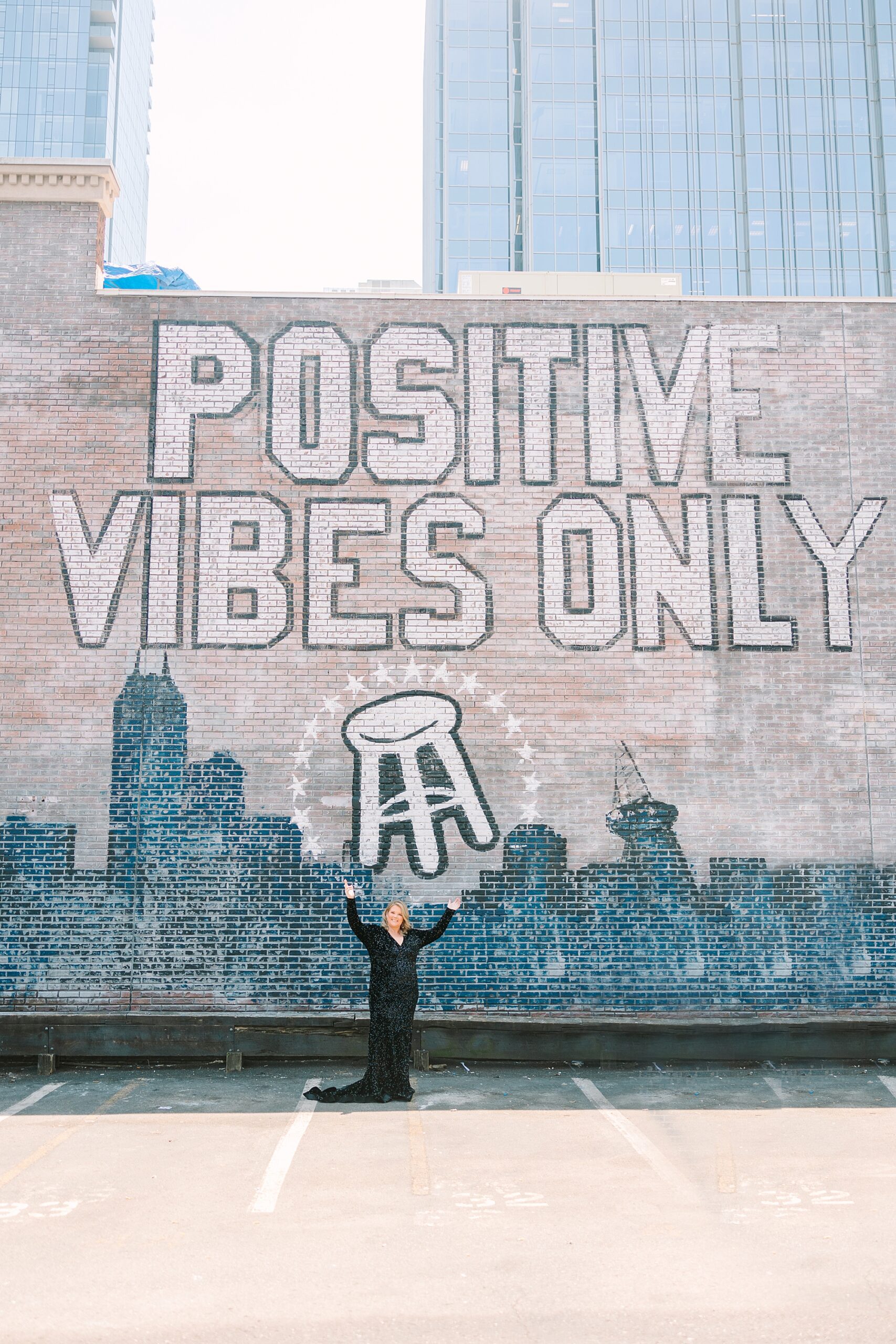 woman poses by mural saying "positive vibes only" on Broadway in Downtown Nashville