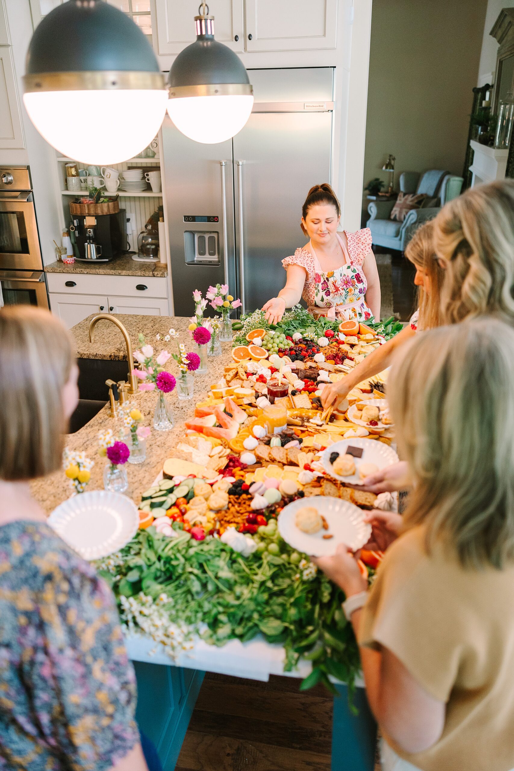 women circle around countertop to reach Pretty Lovely Teas grazing table