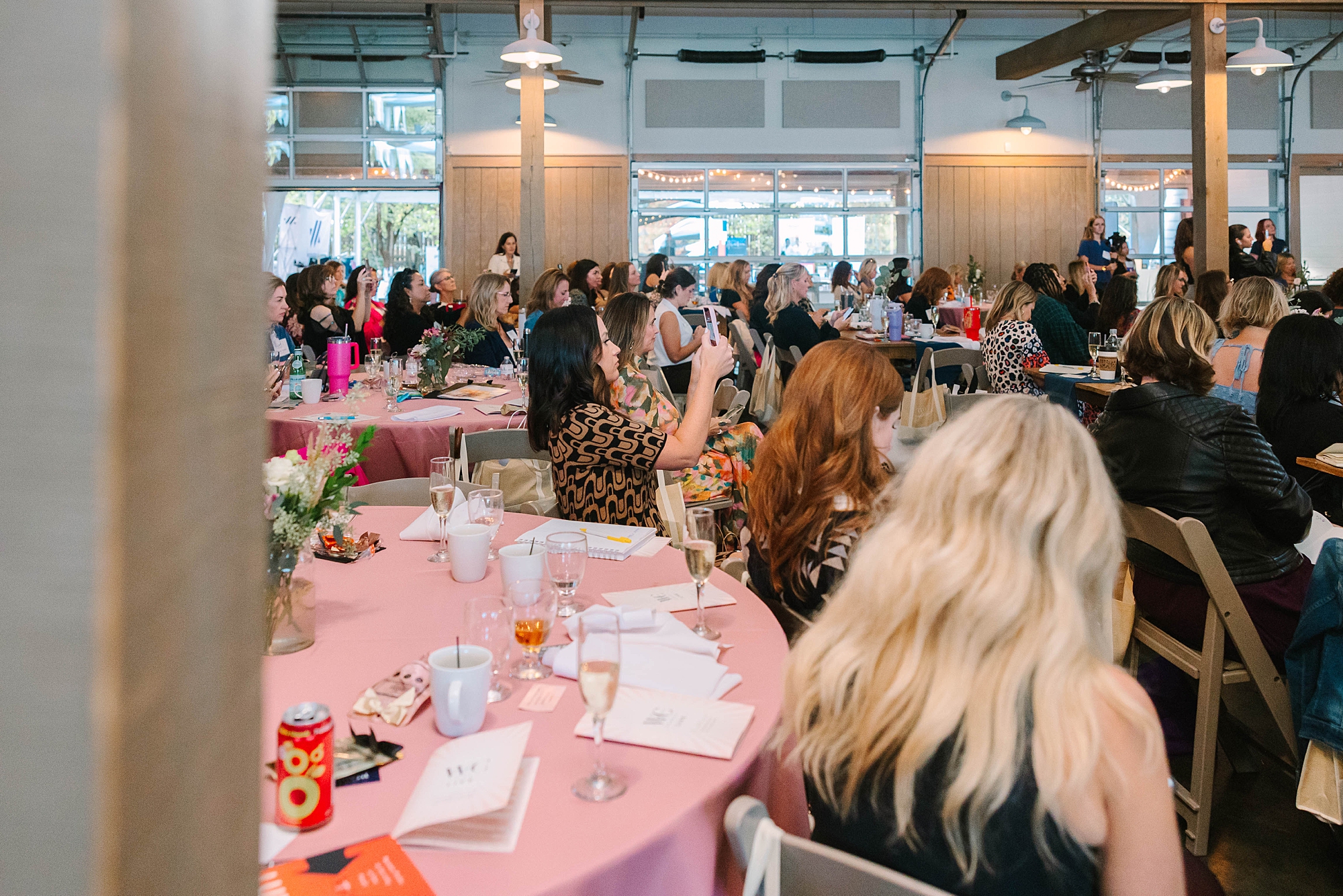 women listen to speakers sitting at tables with pink cloths