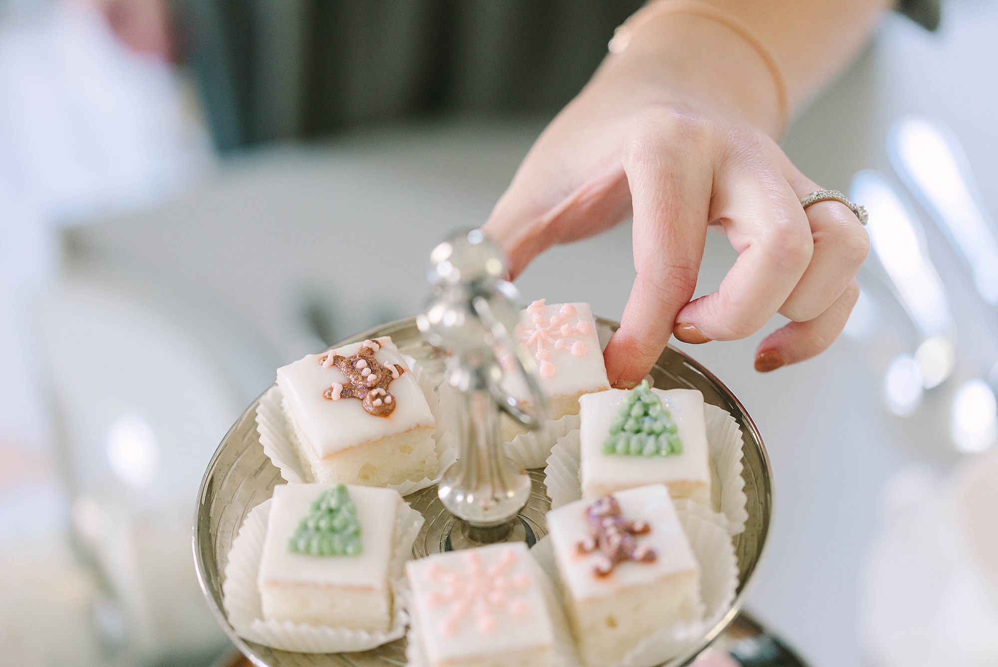 woman reaches for petite four at holiday tea setup