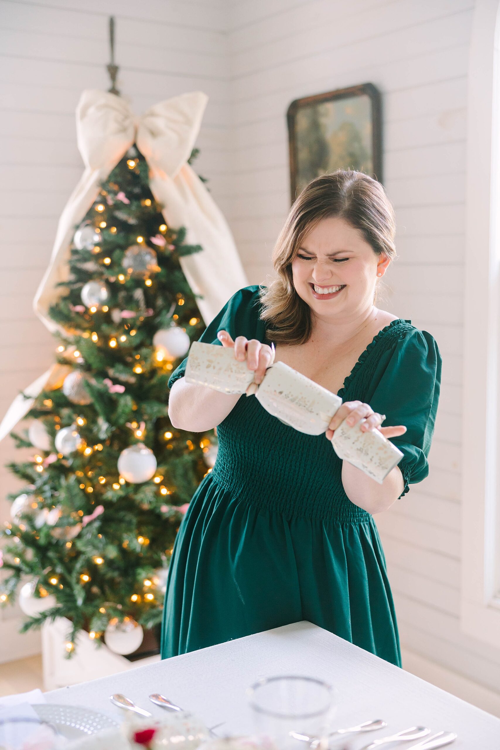 woman in green dress laughs popping holiday cracker at Christmas tea