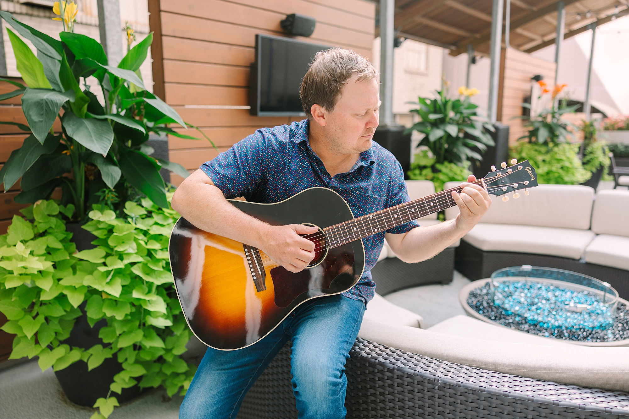 man sits on outdoor furniture playing guitar during Downtown Nashville branding session
