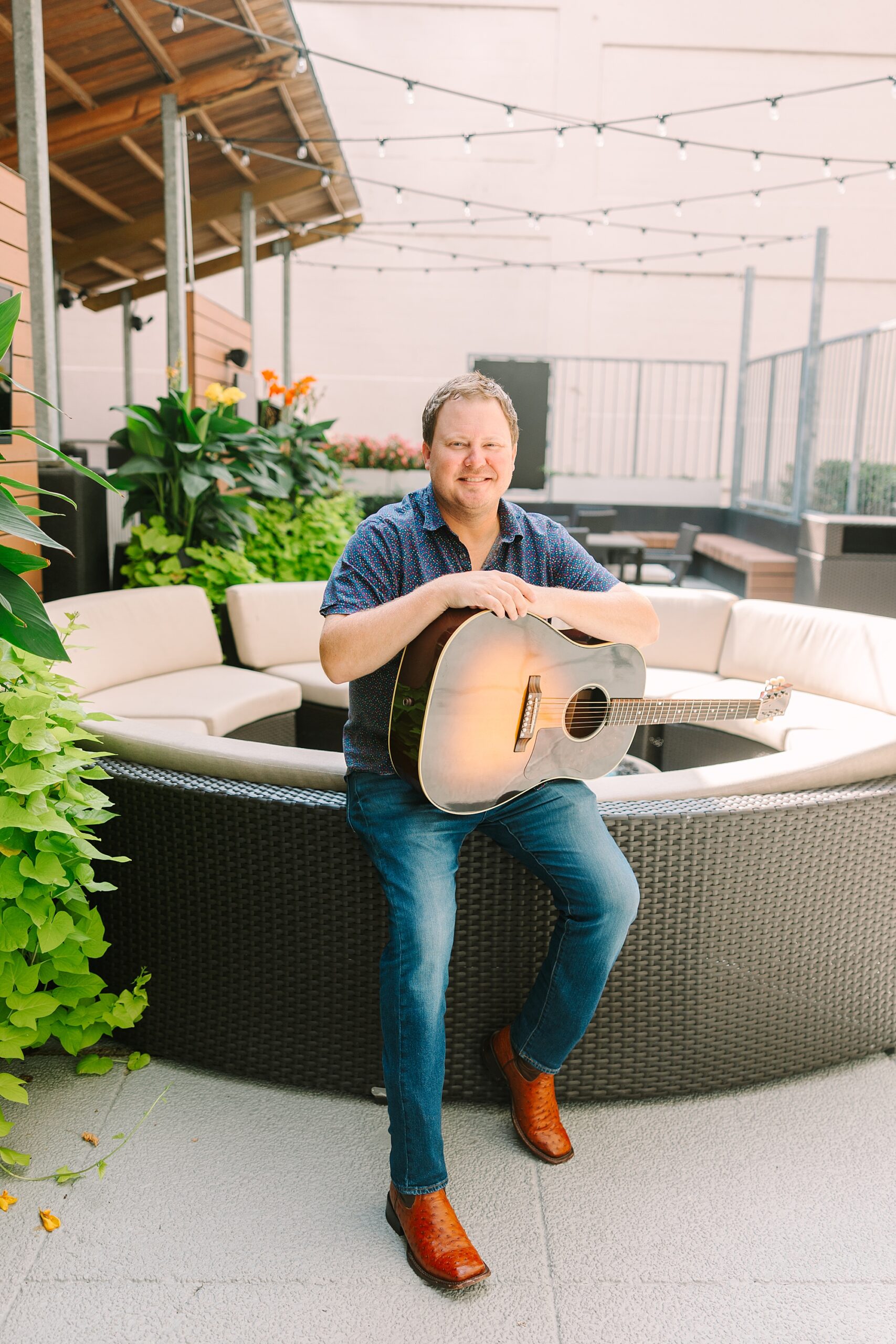 guitar player sits on patio furniture in Downtown Nashville