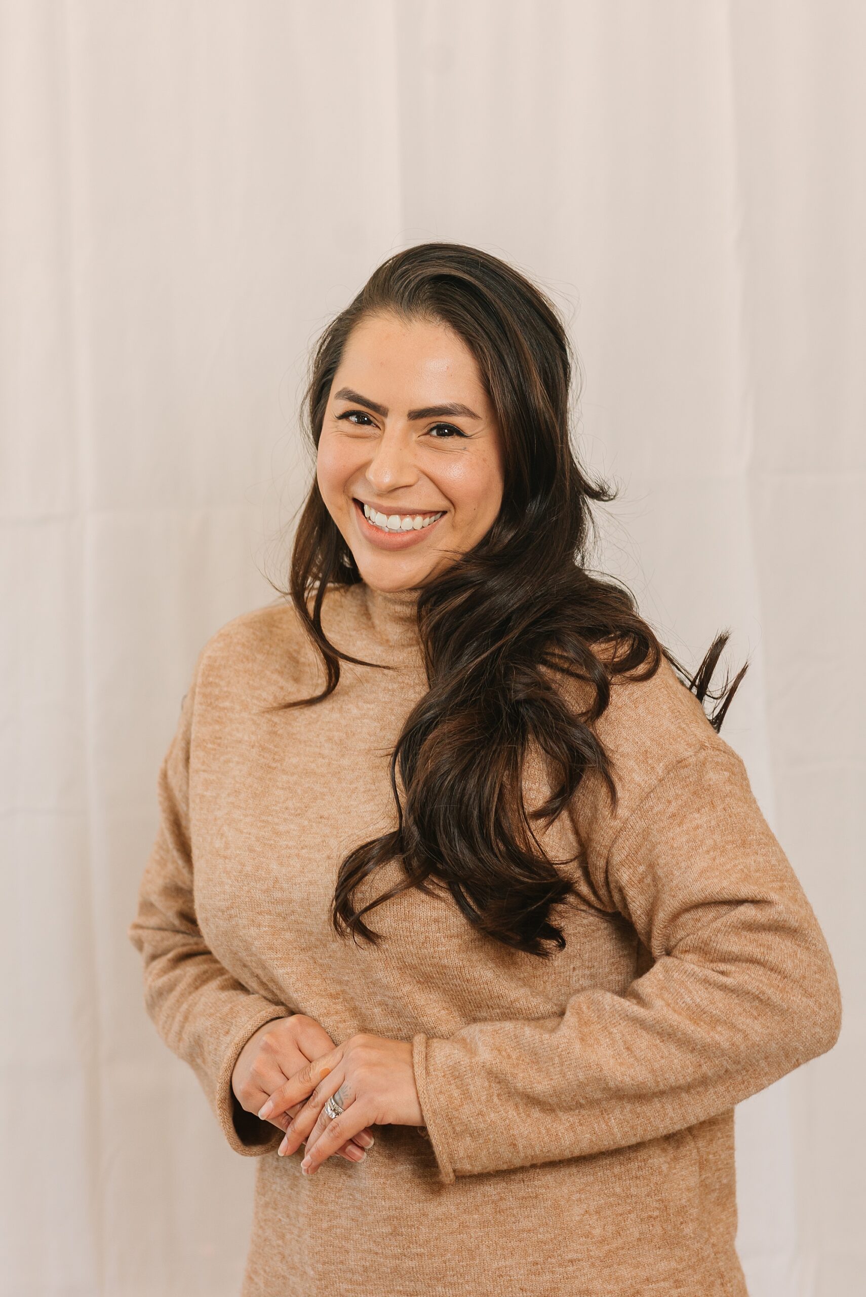 brunette woman in brown turtle neck smiles during quarterly branding portraits in Nashville for salon