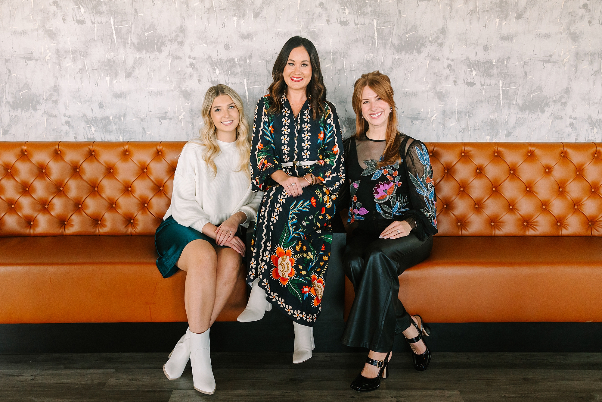 three women sit on orange and yellow sofa during quarterly Nashville branding session